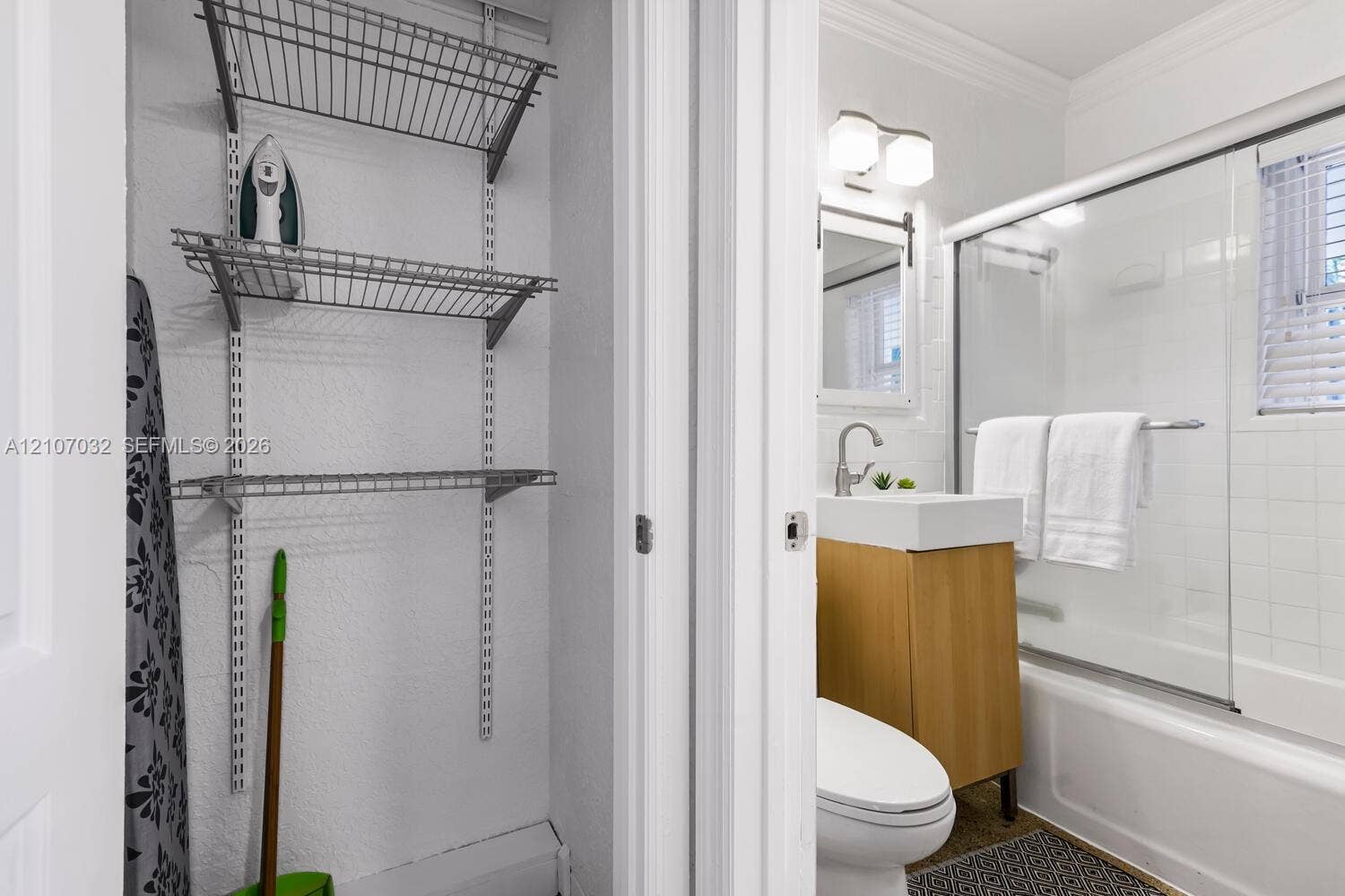 443 NE 17th Way, Fort Lauderdale, FL 33301 Built-in wire shelving, vanity with vessel sink, wall-mounted faucet, and glass-enclosed shower featuring tiled surround