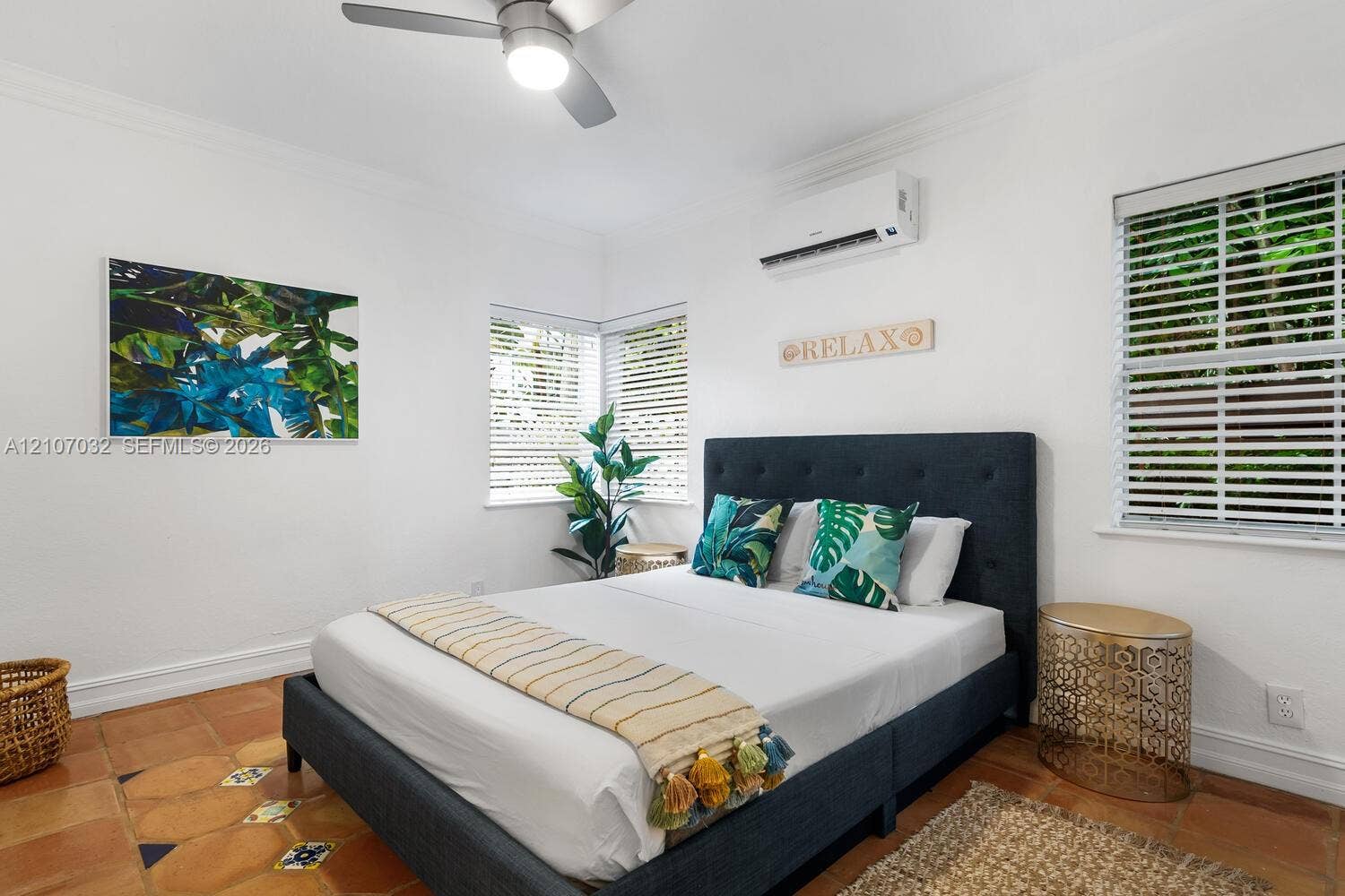 443 NE 17th Way, Fort Lauderdale, FL 33301 Room featuring terra-cotta tile flooring with decorative inlay accents, multi-pane windows with integrated blinds, ceiling fan, and wall-mounted climate control unit