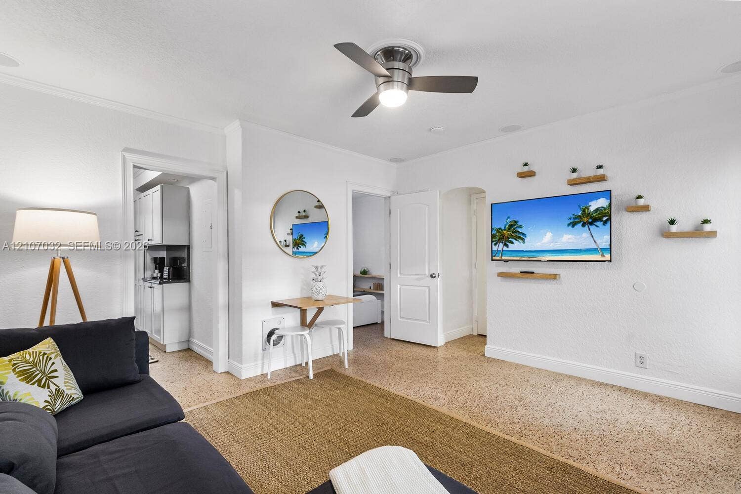 443 NE 17th Way, Fort Lauderdale, FL 33301 Living area featuring terrazzo flooring, a ceiling fan with integrated lighting, and multiple wall-mounted floating shelves