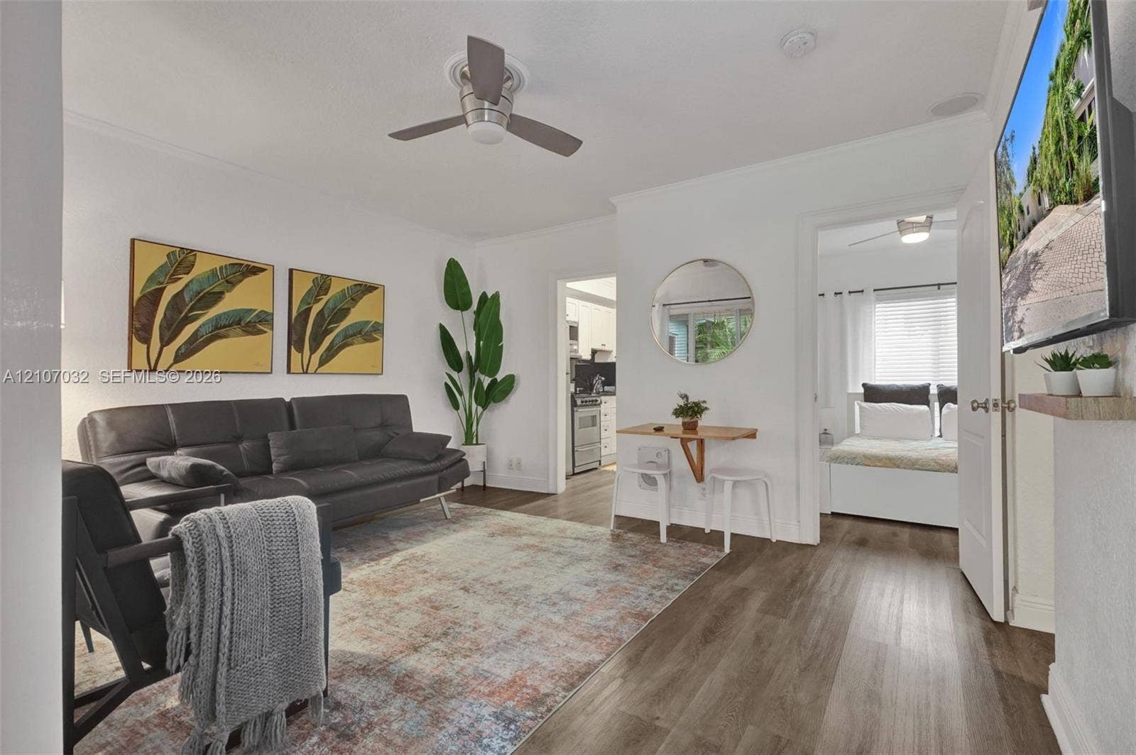443 NE 17th Way, Fort Lauderdale, FL 33301 Living space featuring wood-finish flooring, a ceiling fan, and a wall-mounted television shelf