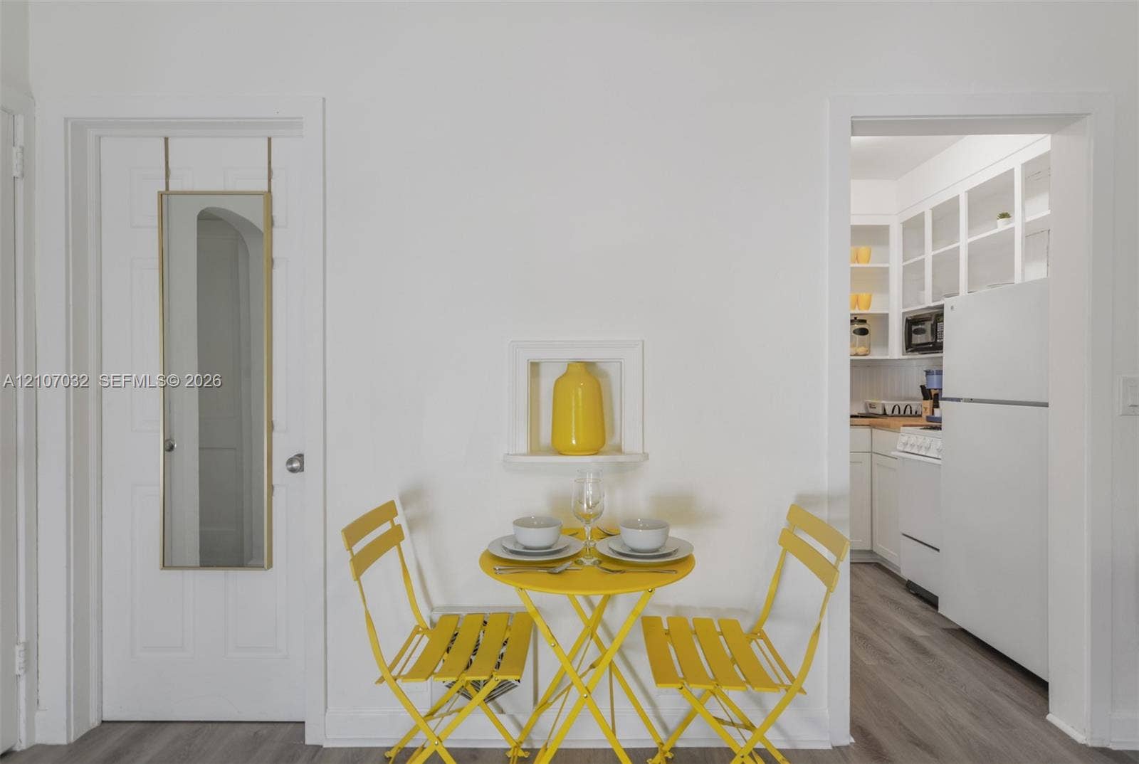 443 NE 17th Way, Fort Lauderdale, FL 33301 Built-in wall niche, wood-finish flooring, white cabinetry with glass-front uppers, and six-panel interior door