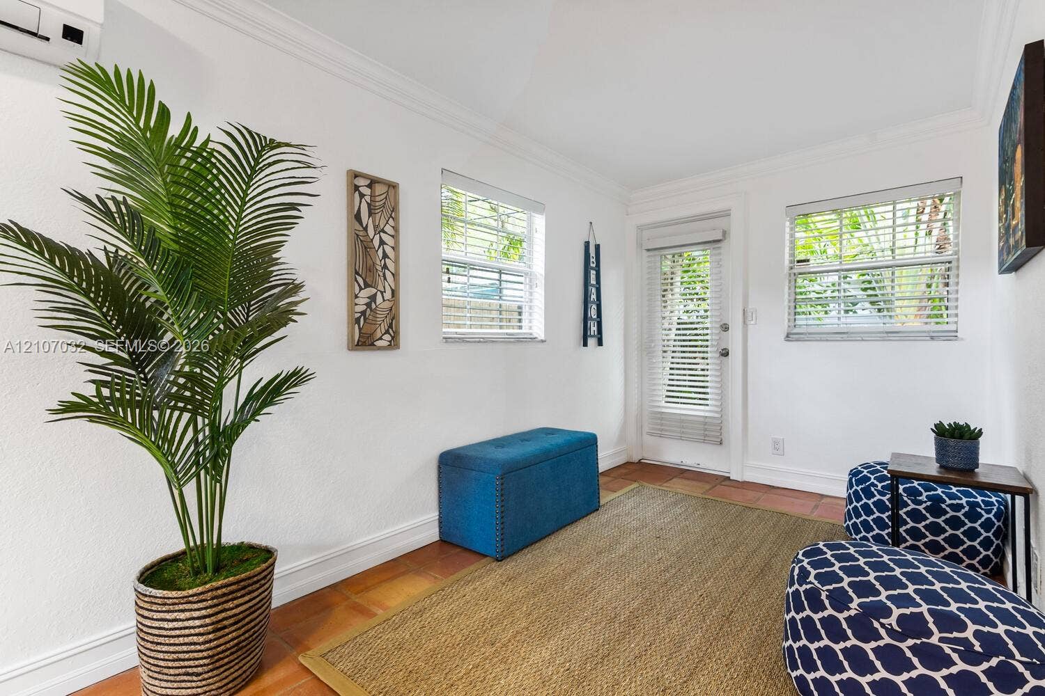 443 NE 17th Way, Fort Lauderdale, FL 33301 Neutral-toned interior featuring ceramic tile flooring, crown molding, two windows with horizontal blinds, and a glass-paneled exterior door