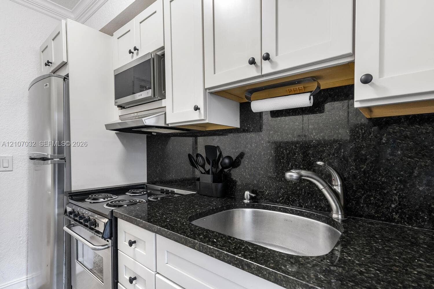 443 NE 17th Way, Fort Lauderdale, FL 33301 Kitchen featuring white shaker-style cabinetry, stone countertops, stainless steel appliances, and a deep-basin stainless steel sink with a high-arch faucet