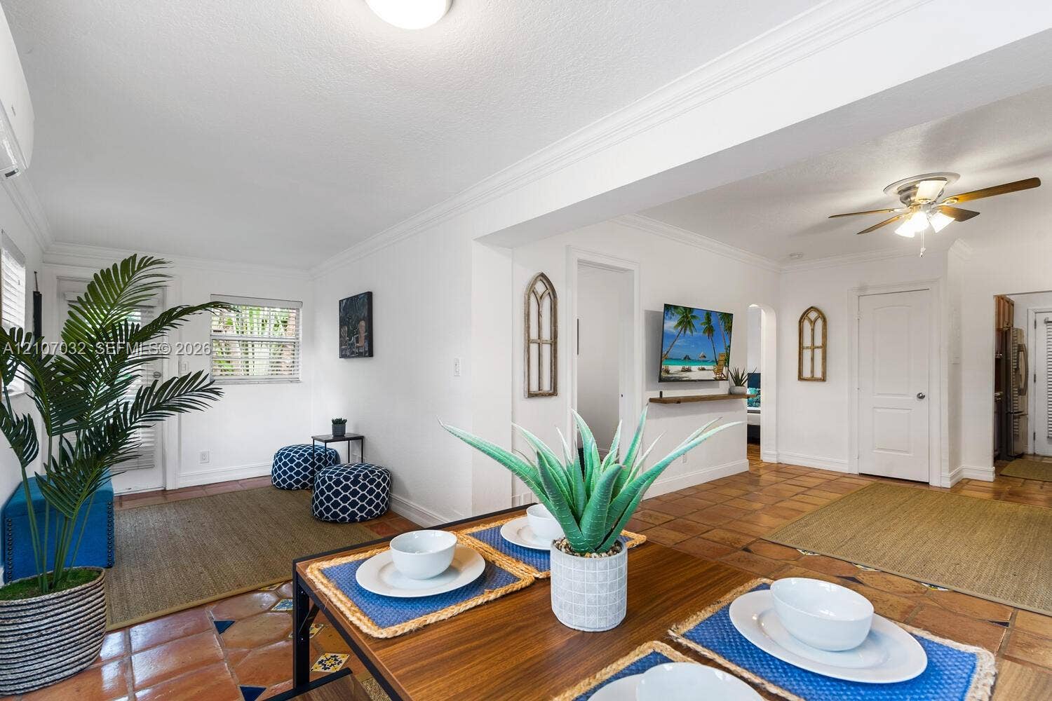 443 NE 17th Way, Fort Lauderdale, FL 33301 Interior space featuring terra cotta tile flooring, crown molding, a ceiling fan with integrated lighting, and a wall-mounted display shelf