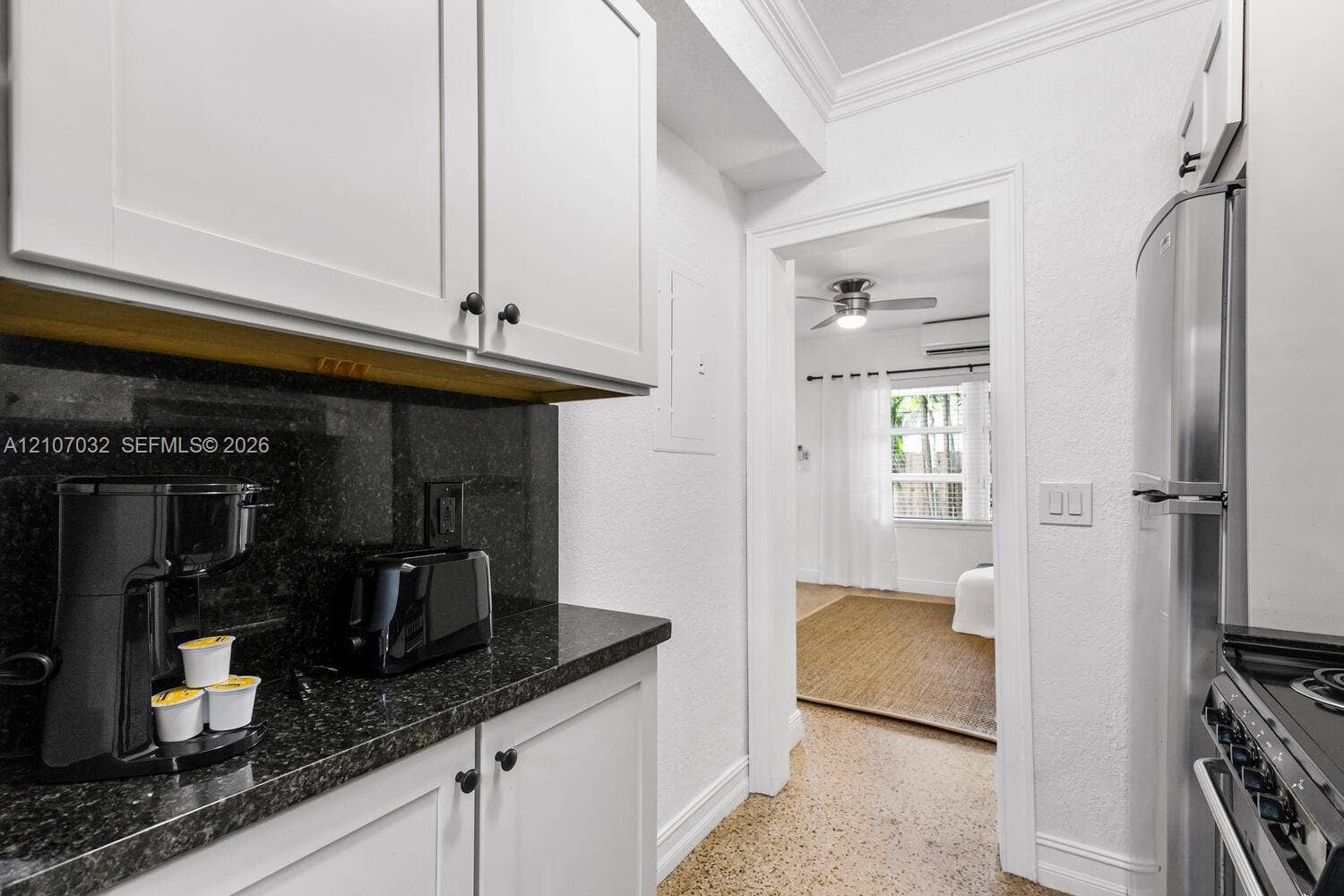 443 NE 17th Way, Fort Lauderdale, FL 33301 Kitchen featuring white Shaker-style cabinetry, dark stone-finish countertops, stainless steel refrigerator, and terrazzo flooring