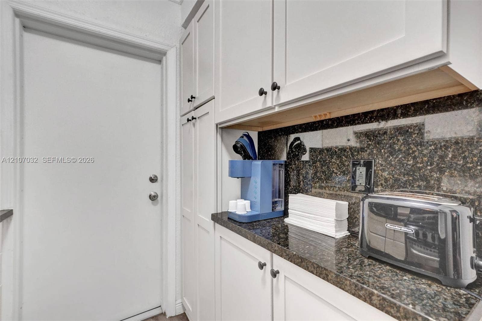 443 NE 17th Way, Fort Lauderdale, FL 33301 White shaker-style cabinetry with dark stone countertops and a coordinating stone backsplash