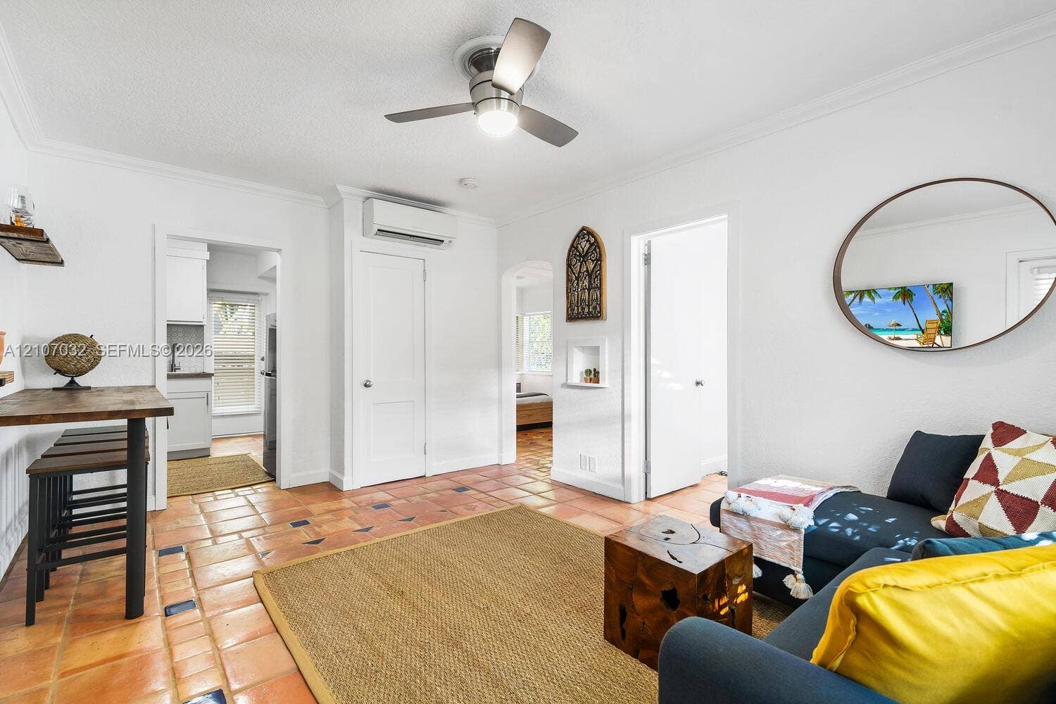 443 NE 17th Way, Fort Lauderdale, FL 33301 Terracotta tile flooring with inlaid decorative tiles, ceiling fan with integrated lighting, wall-mounted ductless air conditioning unit, and arched doorways