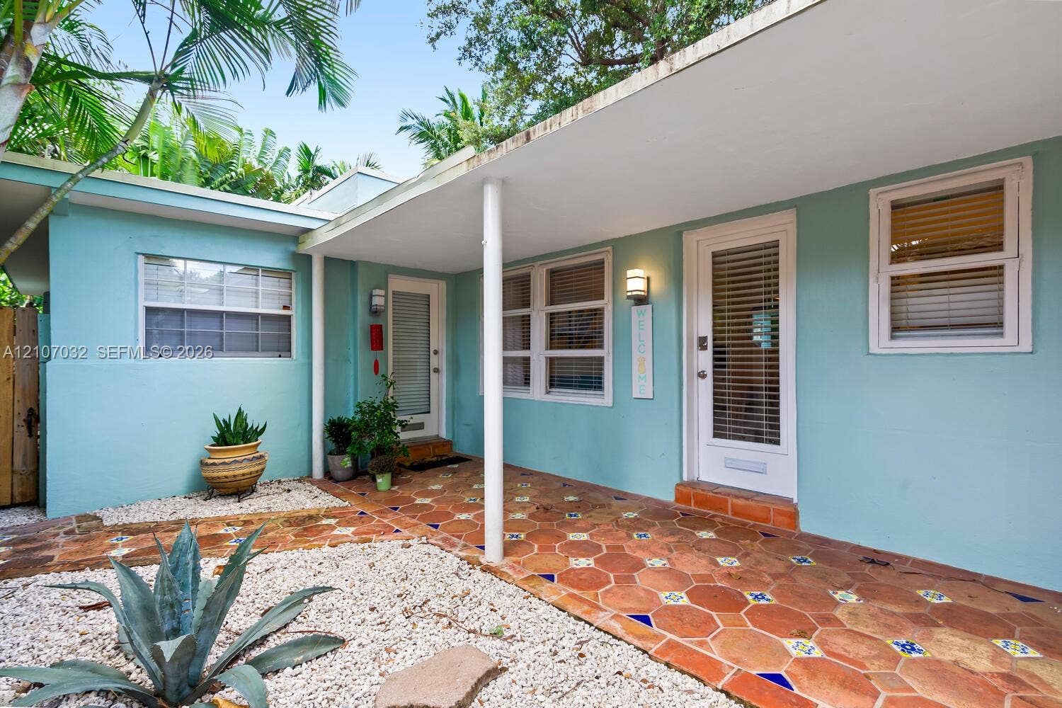 443 NE 17th Way, Fort Lauderdale, FL 33301 Exterior facade featuring light-colored stucco, a covered porch with patterned tile flooring, dual glass-paneled entry doors, and gravel landscaping