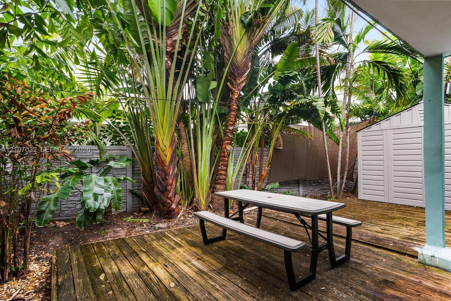 443 NE 17th Way, Fort Lauderdale, FL 33301 Outdoor deck with wood planks, mature tropical landscaping, and a masonry perimeter wall