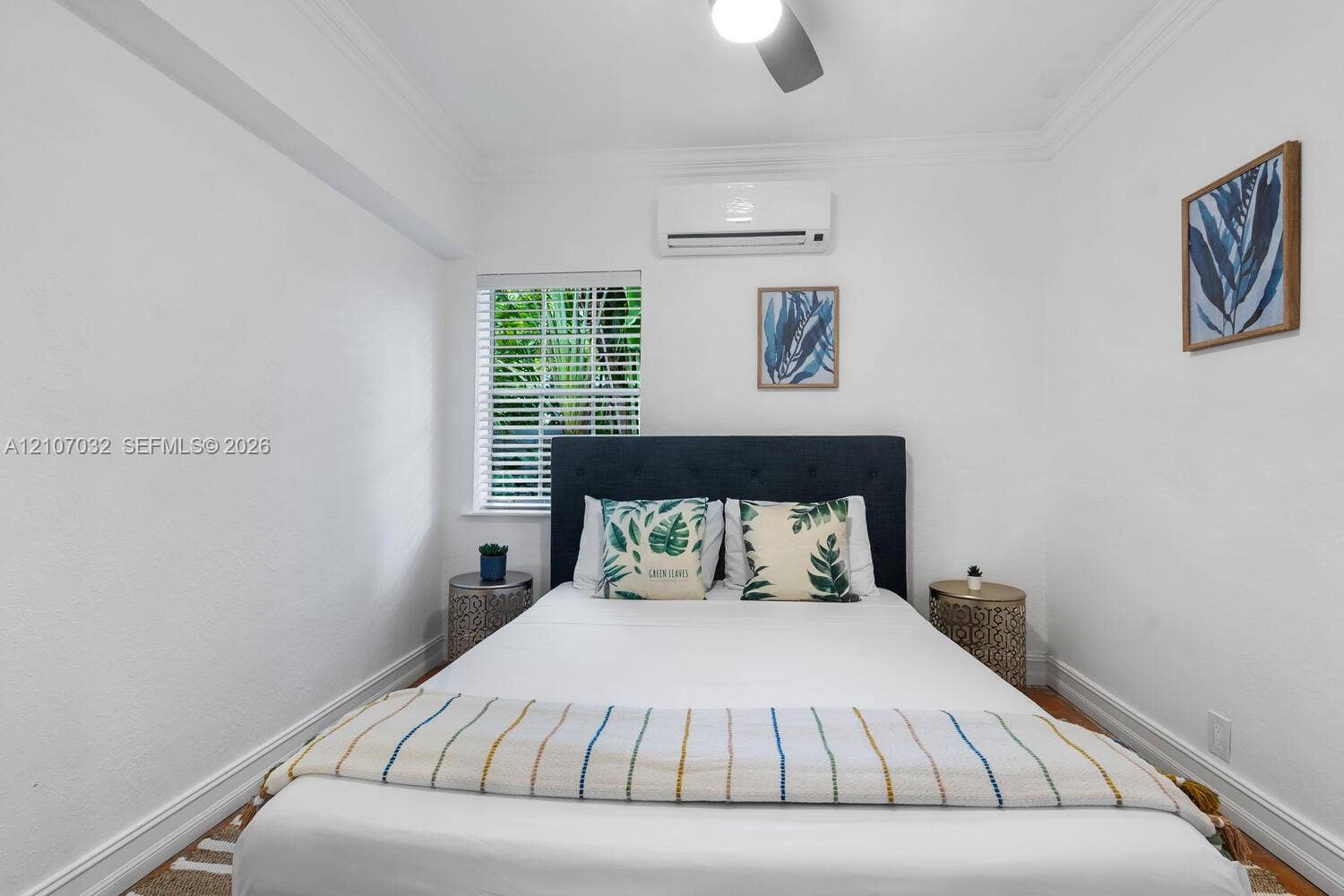 443 NE 17th Way, Fort Lauderdale, FL 33301 Neutral-toned room featuring wood-finish flooring, crown molding, a wall-mounted mini-split HVAC unit, and a single-pane window with horizontal blinds