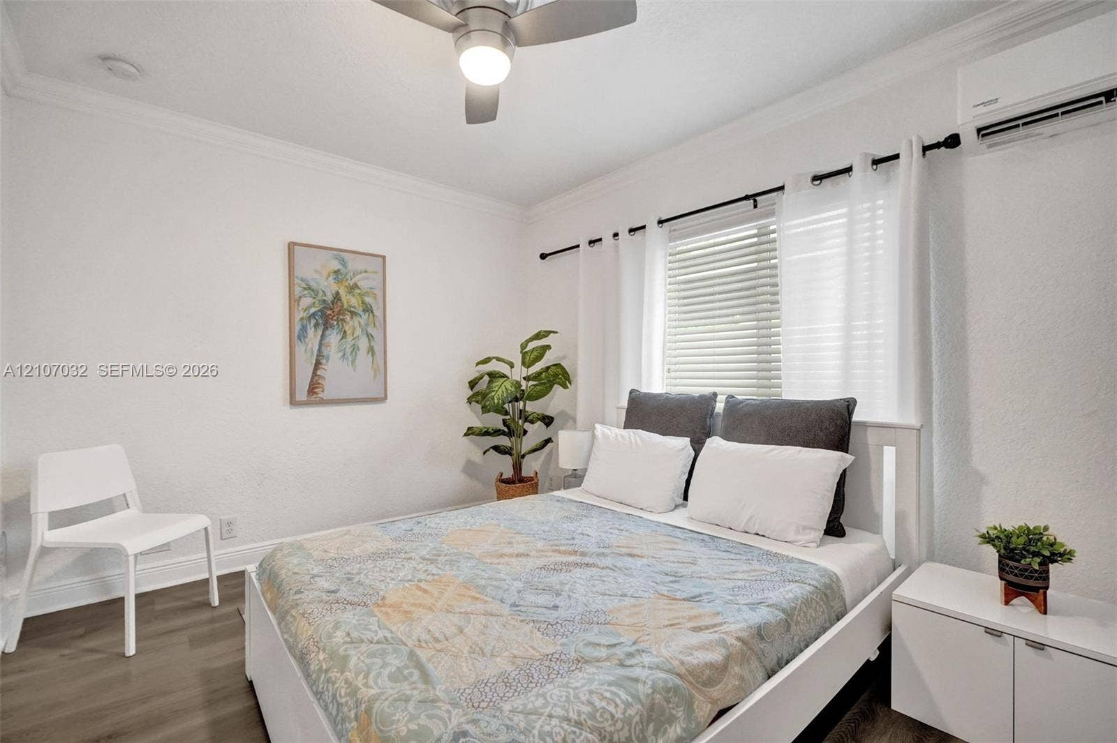 443 NE 17th Way, Fort Lauderdale, FL 33301 Bedroom featuring wood-finish flooring, crown molding, ceiling fan with integrated lighting, wall-mounted ductless air conditioning unit, and horizontal blinds