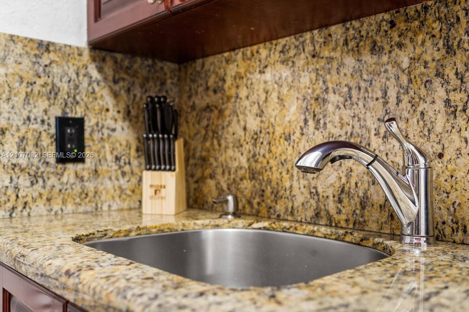 443 NE 17th Way, Fort Lauderdale, FL 33301 Undermount stainless steel sink featuring a chrome pull-down faucet, matching stone countertop, and full-height stone backsplash