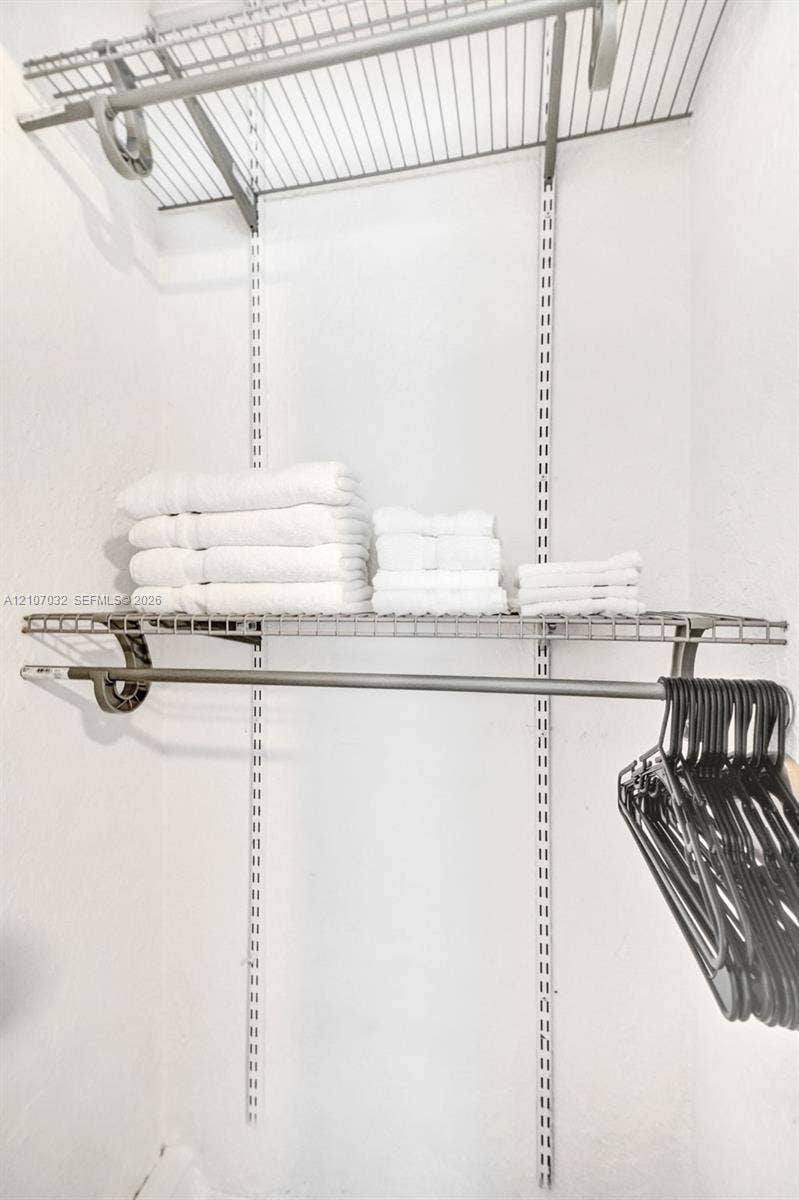 443 NE 17th Way, Fort Lauderdale, FL 33301 Adjustable storage system featuring white wire shelving, wall-mounted tracks, and an integrated hanging rod
