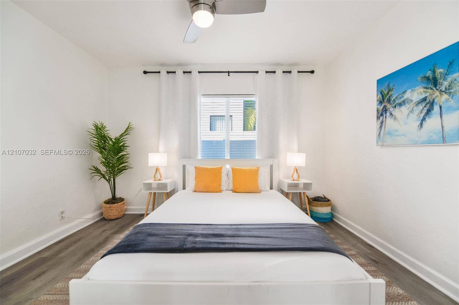 443 NE 17th Way, Fort Lauderdale, FL 33301 Neutral-toned interior featuring wood-finish flooring, a central ceiling fan with integrated lighting, and a window with a curtain rod fixture