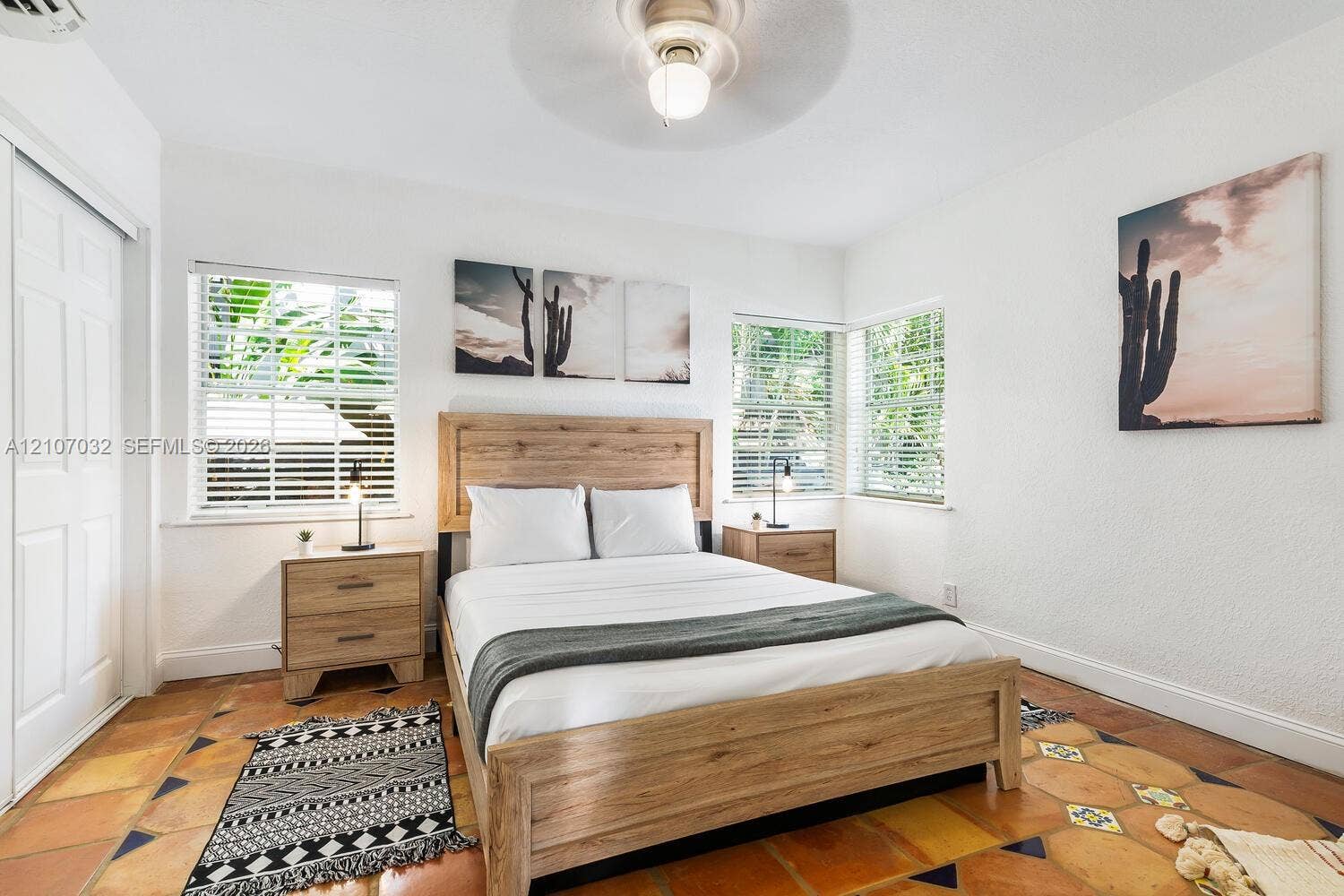 Interior space featuring terracotta floor tile, dual-aspect windows with horizontal blinds, and a ceiling-mounted light fixture with fan