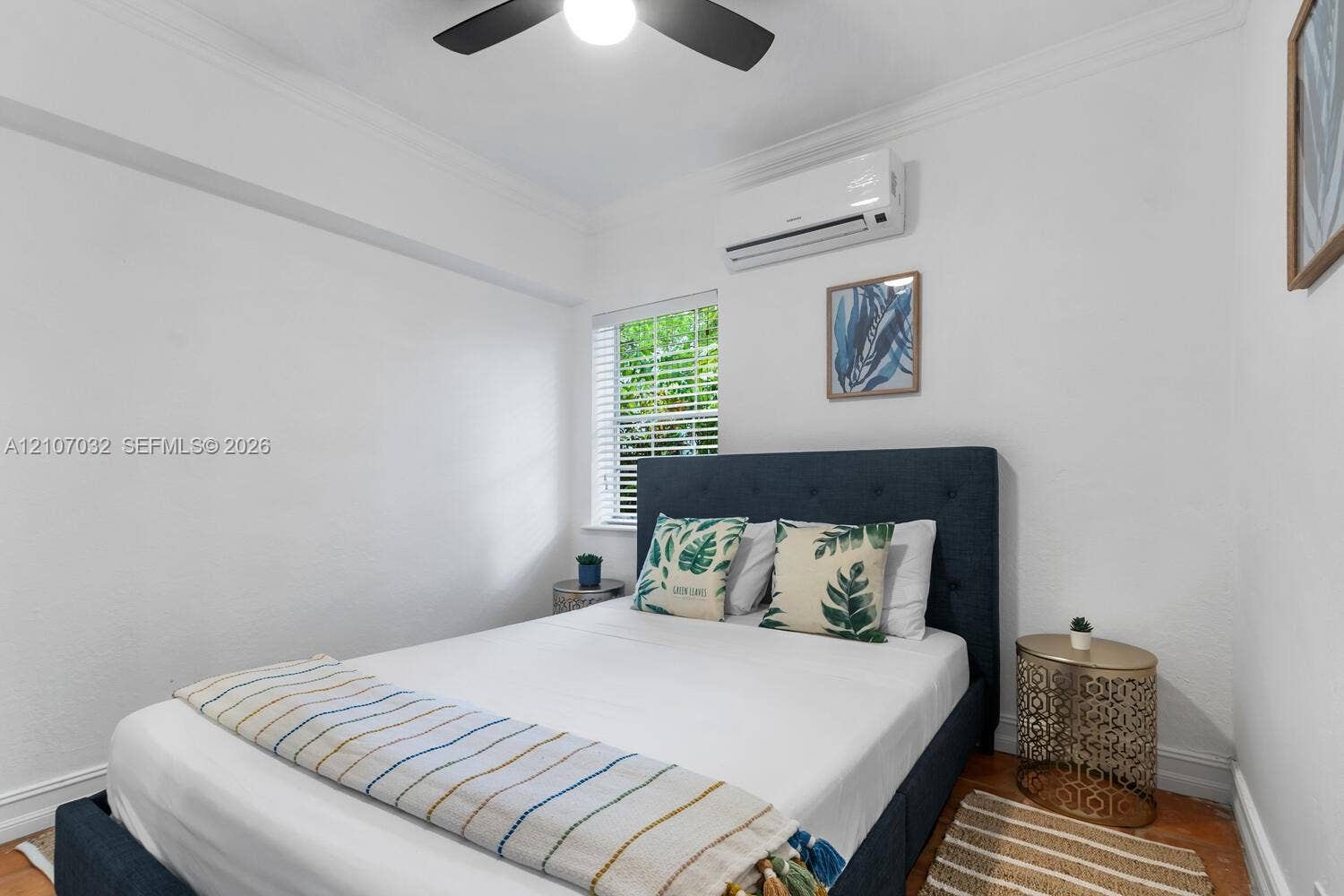 443 NE 17th Way, Fort Lauderdale, FL 33301 Interior space featuring wood-finish flooring, a wall-mounted ductless air conditioning unit, a multi-blade ceiling fan, and a window with white blinds