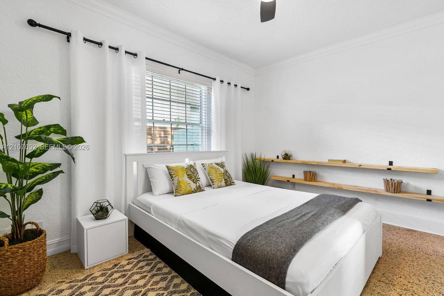 443 NE 17th Way, Fort Lauderdale, FL 33301 Bedroom interior featuring textured walls, crown molding, double-hung window with metal horizontal blinds, and dual natural wood-finish wall-mounted floating shelves