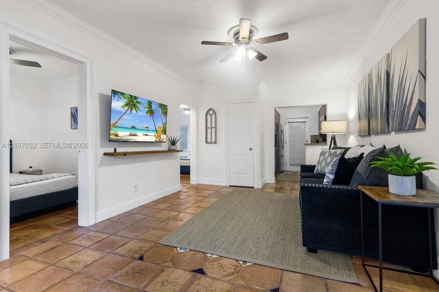 443 NE 17th Way, Fort Lauderdale, FL 33301 Interior space featuring tile flooring, crown molding, a central ceiling fan with integrated lighting, and a custom wood wall-mounted shelf