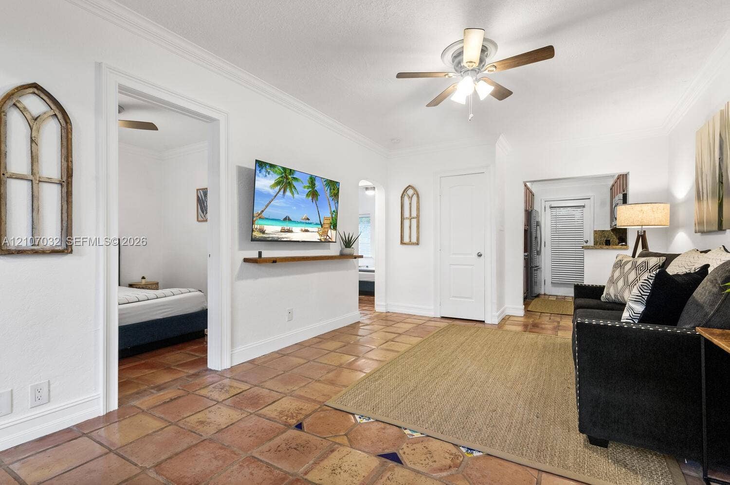443 NE 17th Way, Fort Lauderdale, FL 33301 Interior space featuring terracotta tile flooring, crown molding, a ceiling fan with integrated lighting, and a wall-mounted wooden shelf