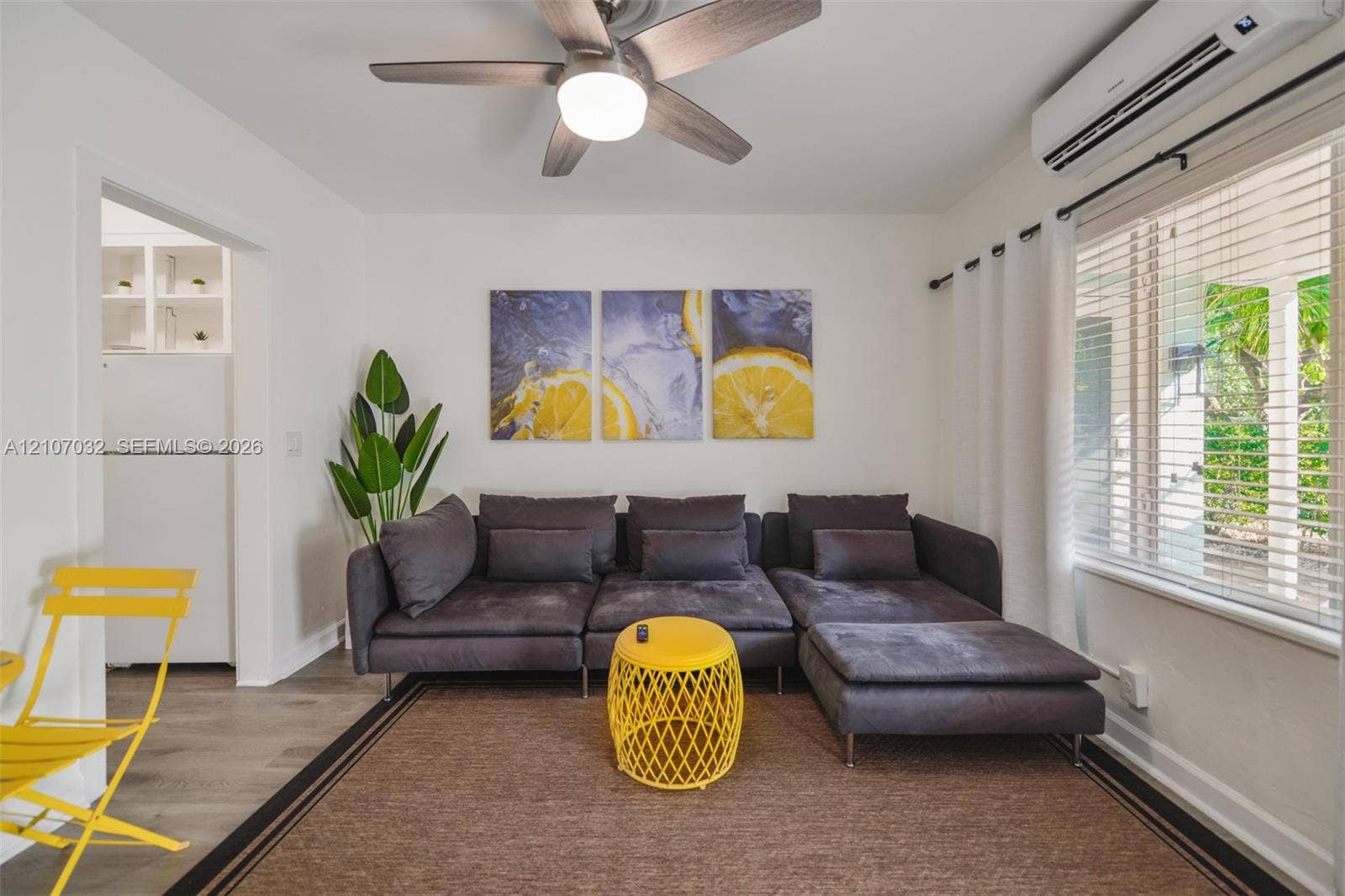 443 NE 17th Way, Fort Lauderdale, FL 33301 Living area featuring wood-finish flooring, a wall-mounted ductless climate control unit, and a ceiling fan with integrated lighting