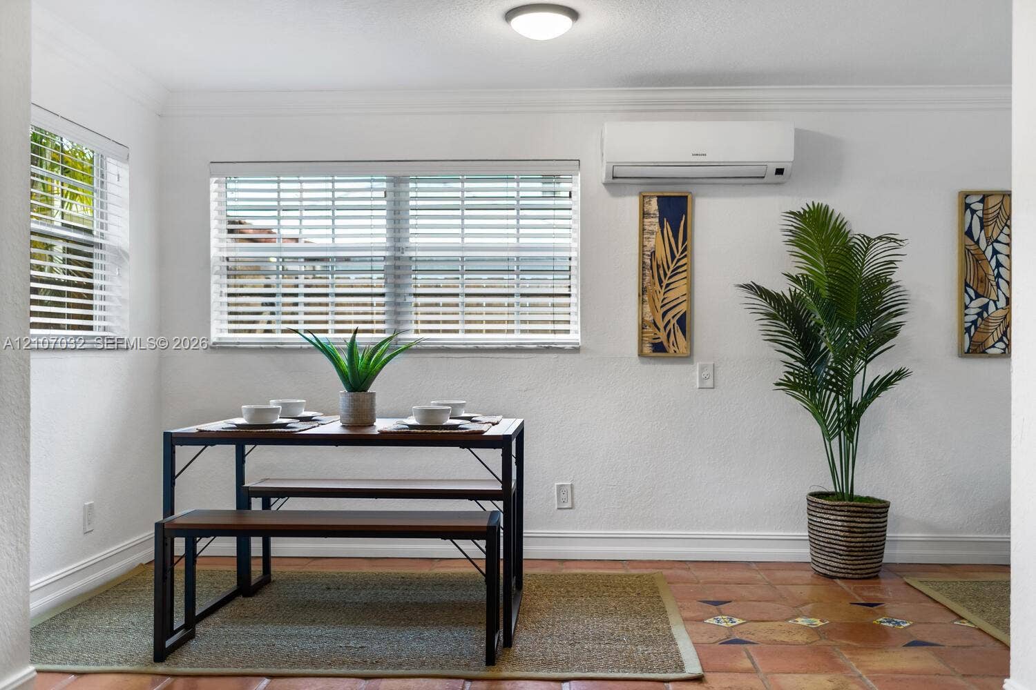 443 NE 17th Way, Fort Lauderdale, FL 33301 Room featuring terra cotta tile flooring, white walls with crown molding, wall-mounted ductless air conditioning unit, and dual windows with horizontal blinds