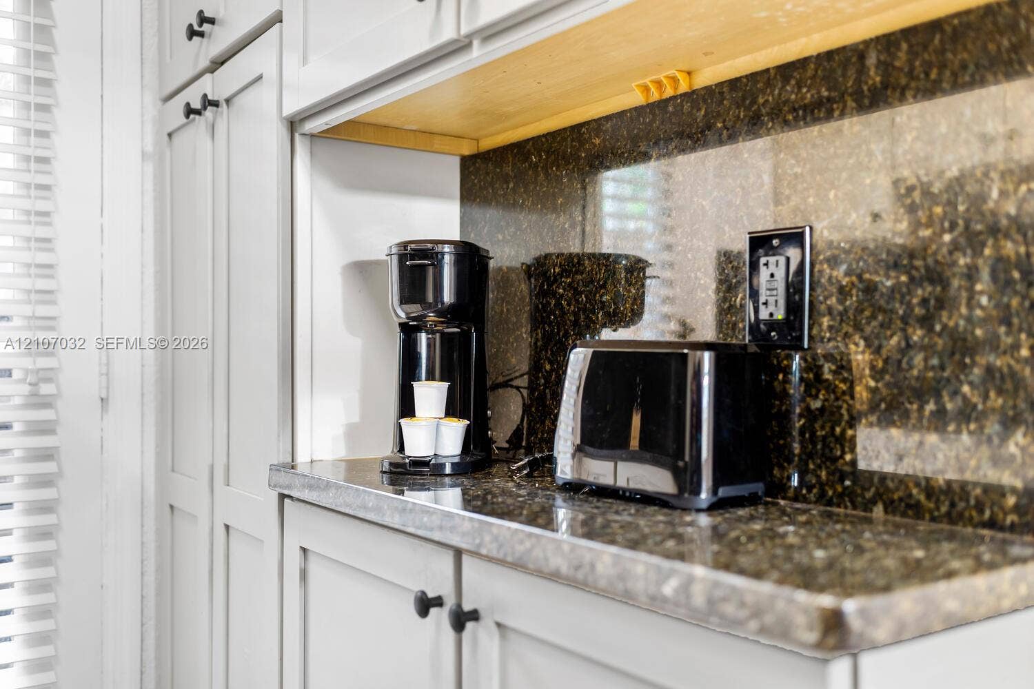 443 NE 17th Way, Fort Lauderdale, FL 33301 Custom cabinetry with matte black hardware, stone-finish countertops, coordinating backsplash, and open wood shelving