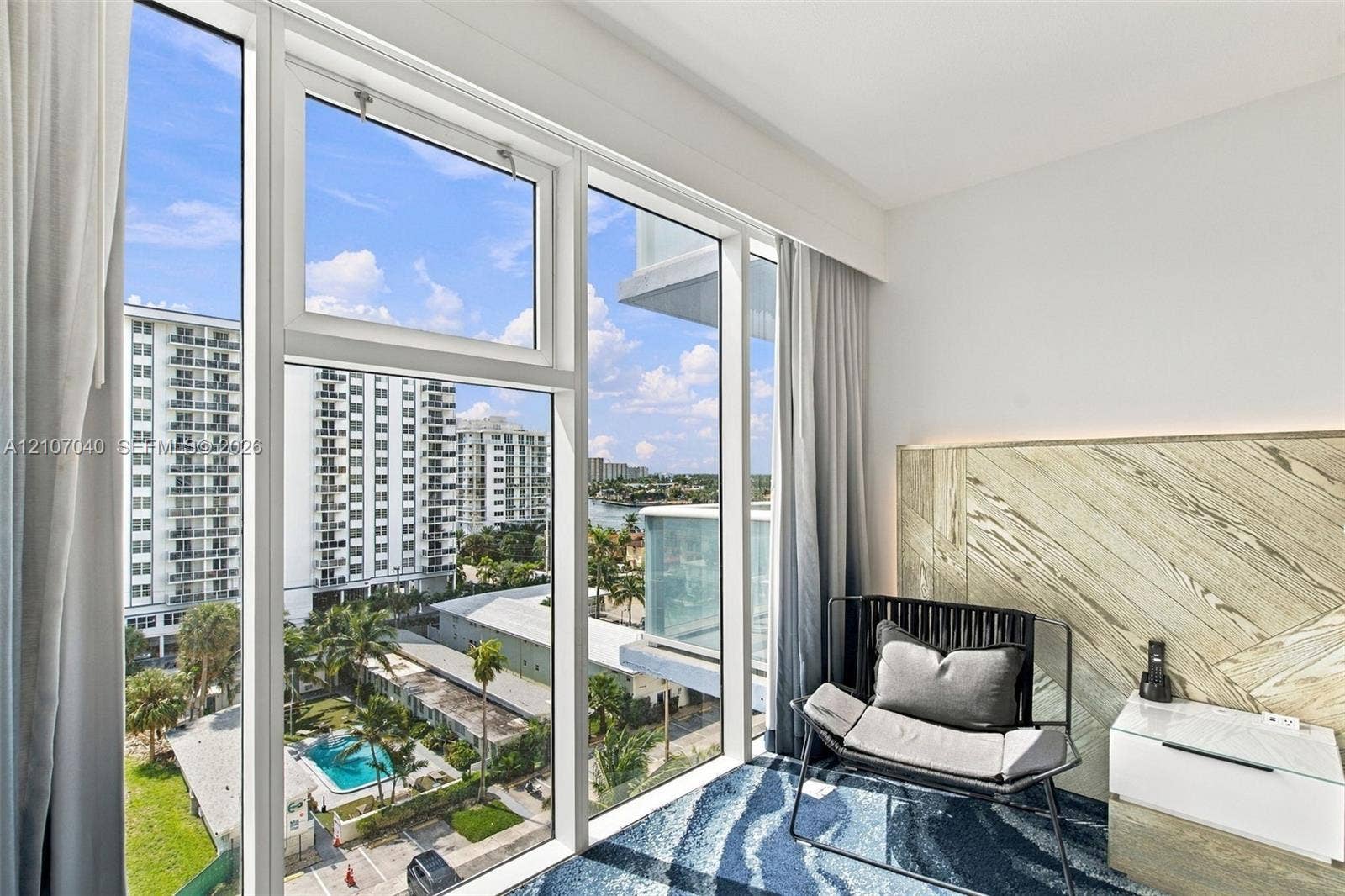 3101 Bayshore Drive, #707, Fort Lauderdale, FL 33304 Floor-to-ceiling windows, custom wood-paneled accent wall with integrated cove lighting, and built-in floating bedside cabinetry