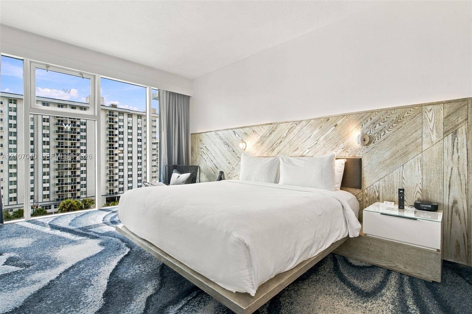 3101 Bayshore Drive, #707, Fort Lauderdale, FL 33304 Floor-to-ceiling windows, custom wood-paneled accent wall, built-in platform bed frame, and wall-mounted reading lights