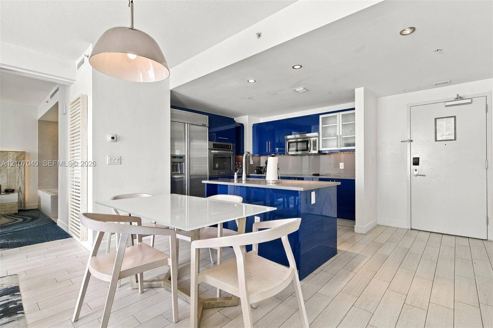 3101 Bayshore Drive, #707, Fort Lauderdale, FL 33304 Kitchen featuring high-gloss blue cabinetry, stone-finish countertops, stainless steel appliances, recessed ceiling lighting, and tile flooring