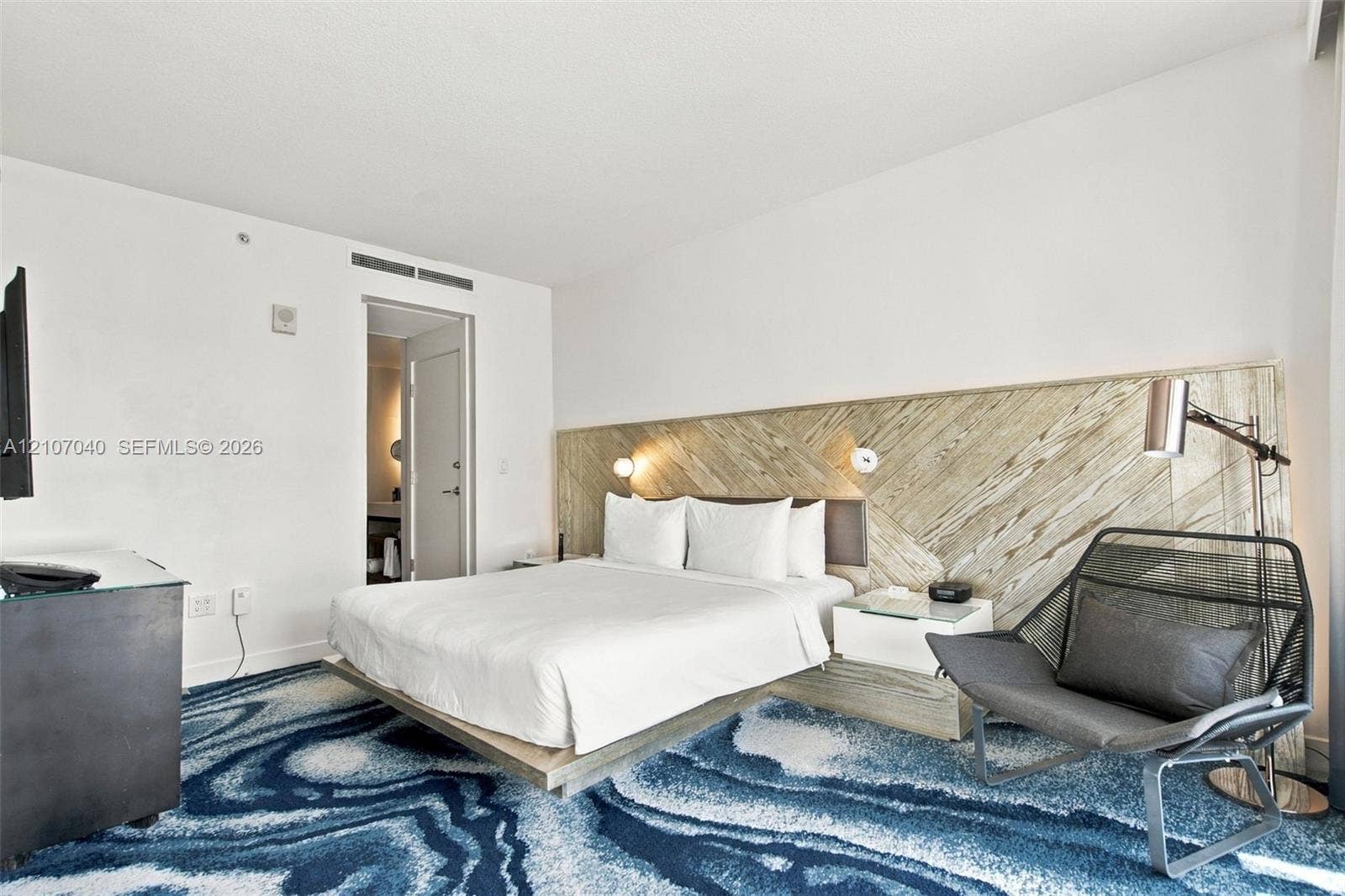 3101 Bayshore Drive, #707, Fort Lauderdale, FL 33304 Bedroom featuring a diagonal wood-finish accent wall, built-in floating nightstands, and wall-mounted reading lights