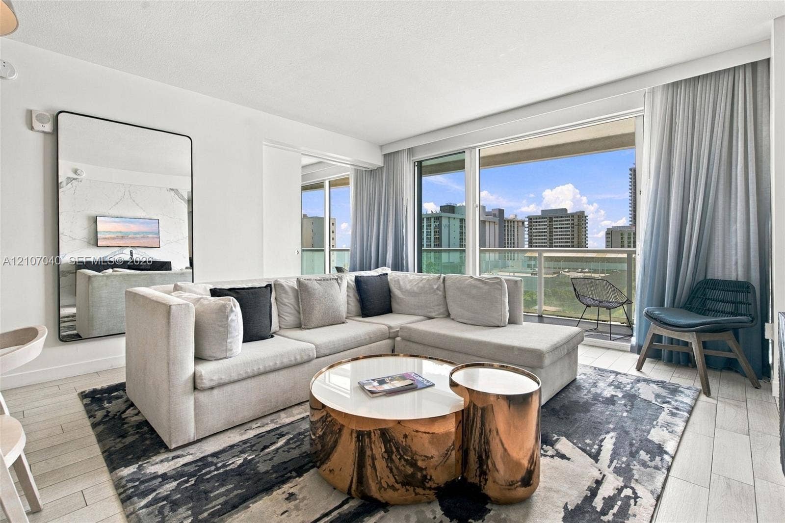 3101 Bayshore Drive, #707, Fort Lauderdale, FL 33304 Living area featuring floor-to-ceiling glass sliding doors, private balcony, large format tile flooring, and a stone-clad accent wall