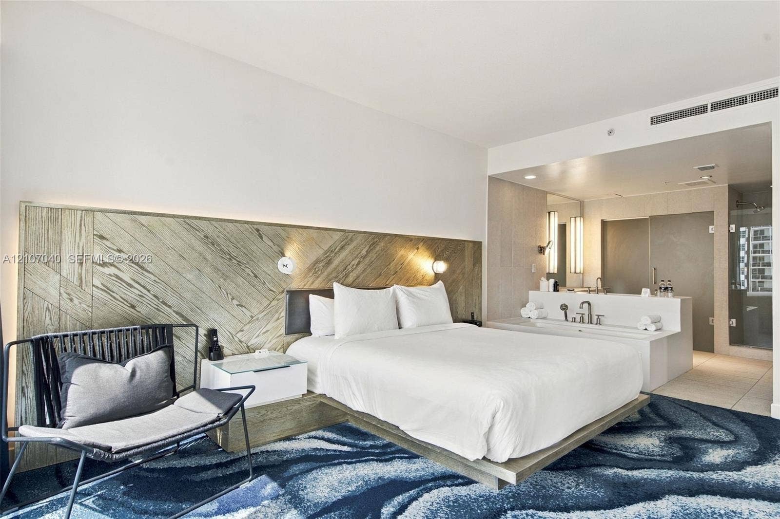 3101 Bayshore Drive, #707, Fort Lauderdale, FL 33304 Diagonally patterned wood-finish headboard, built-in floating bed frame, integrated bedside tables, and open-concept bathroom featuring a soaking tub
