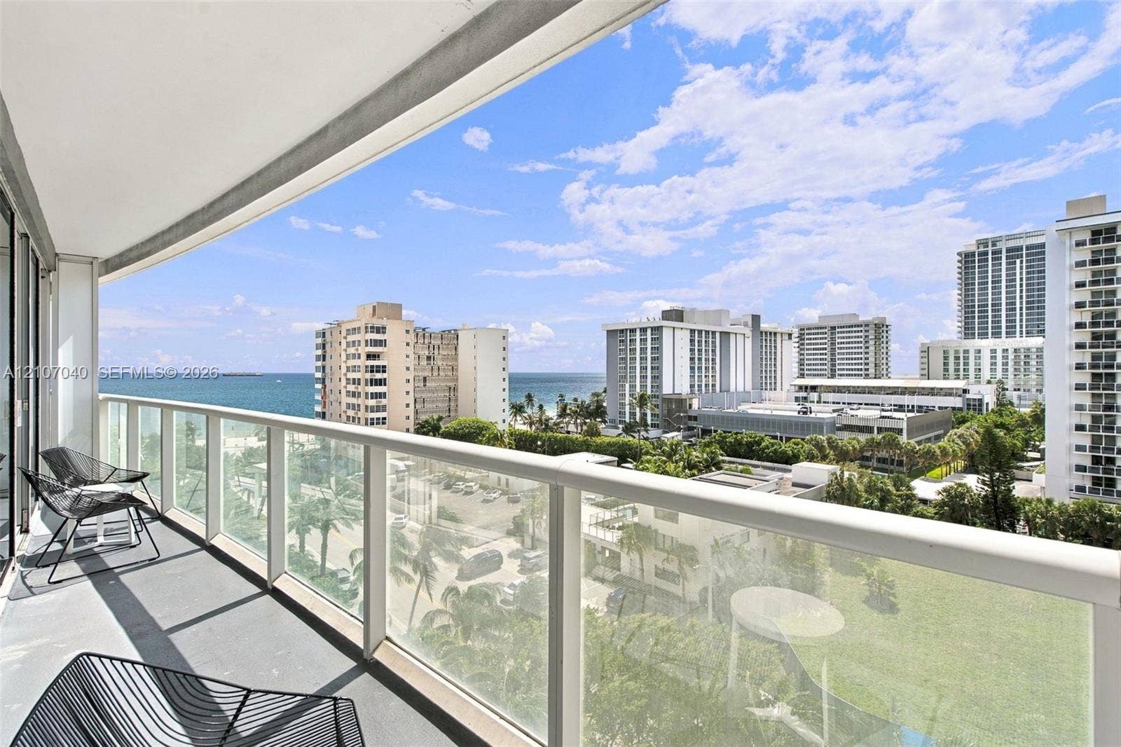 3101 Bayshore Drive, #707, Fort Lauderdale, FL 33304 Private covered balcony featuring a glass panel railing, concrete flooring, and panoramic coastal and urban scenery
