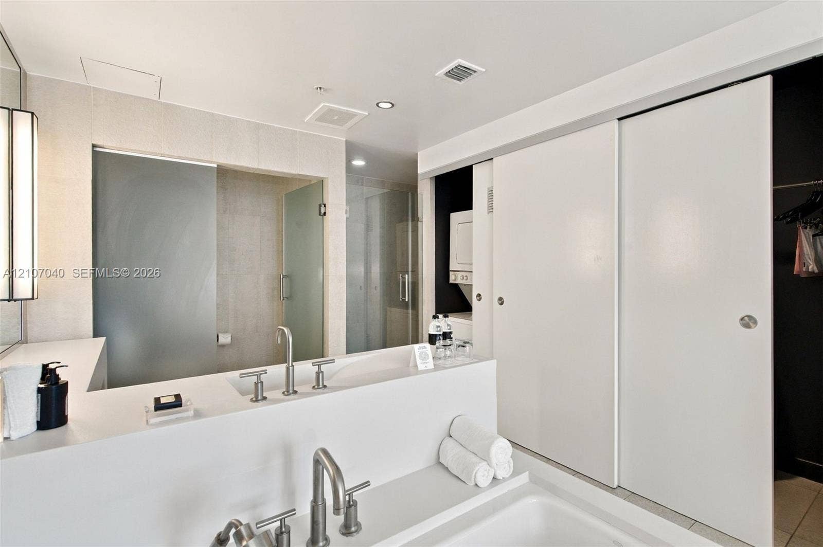 3101 Bayshore Drive, #707, Fort Lauderdale, FL 33304 Modern bathroom featuring a rectangular vessel sink with a bridge-style faucet, white solid-surface countertop, walk-in glass shower enclosure, and sliding panel doors