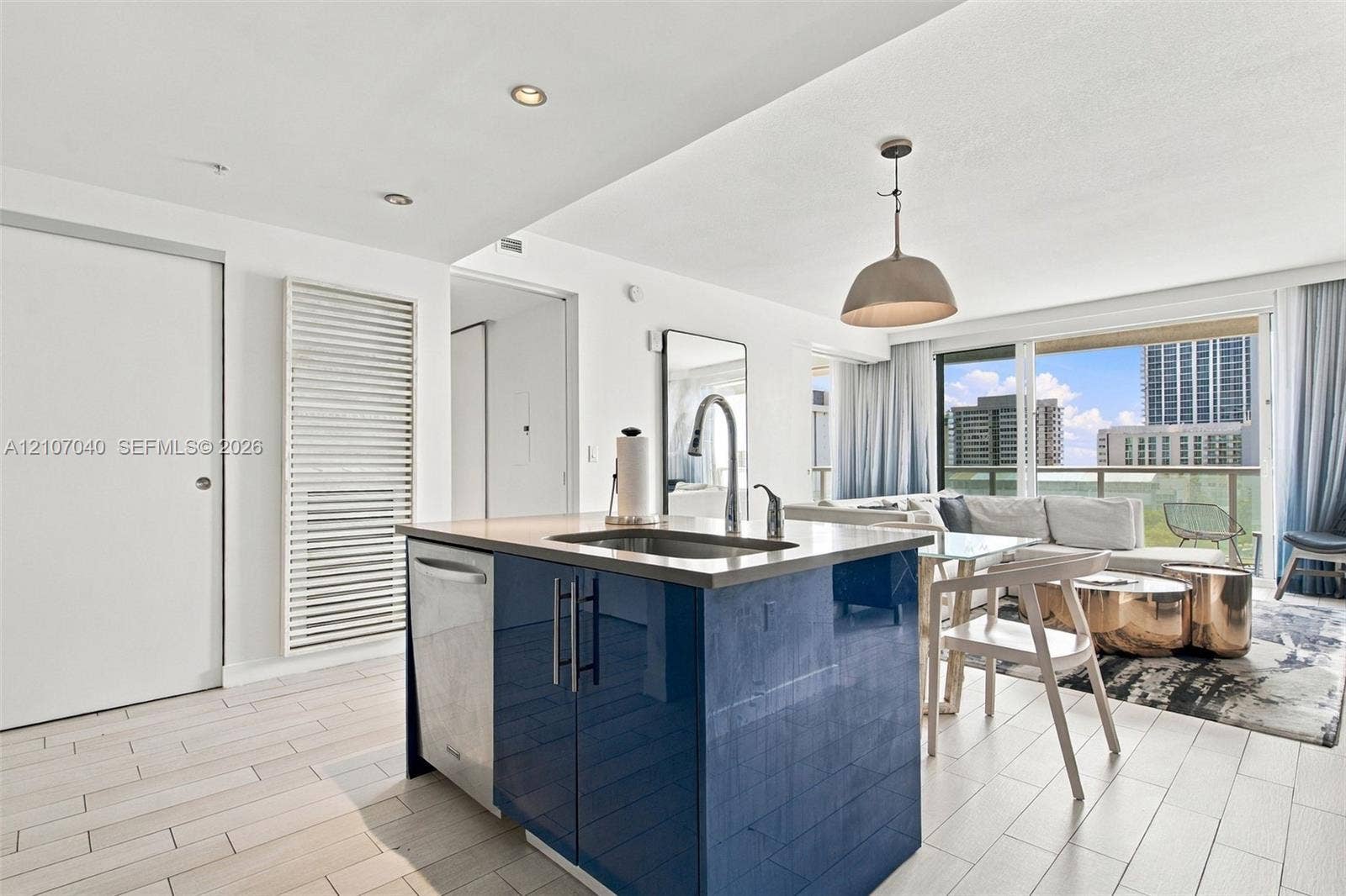 3101 Bayshore Drive, #707, Fort Lauderdale, FL 33304 Kitchen island featuring high-gloss blue cabinetry, a stainless steel undermount sink, a gooseneck faucet, and light-toned tile flooring