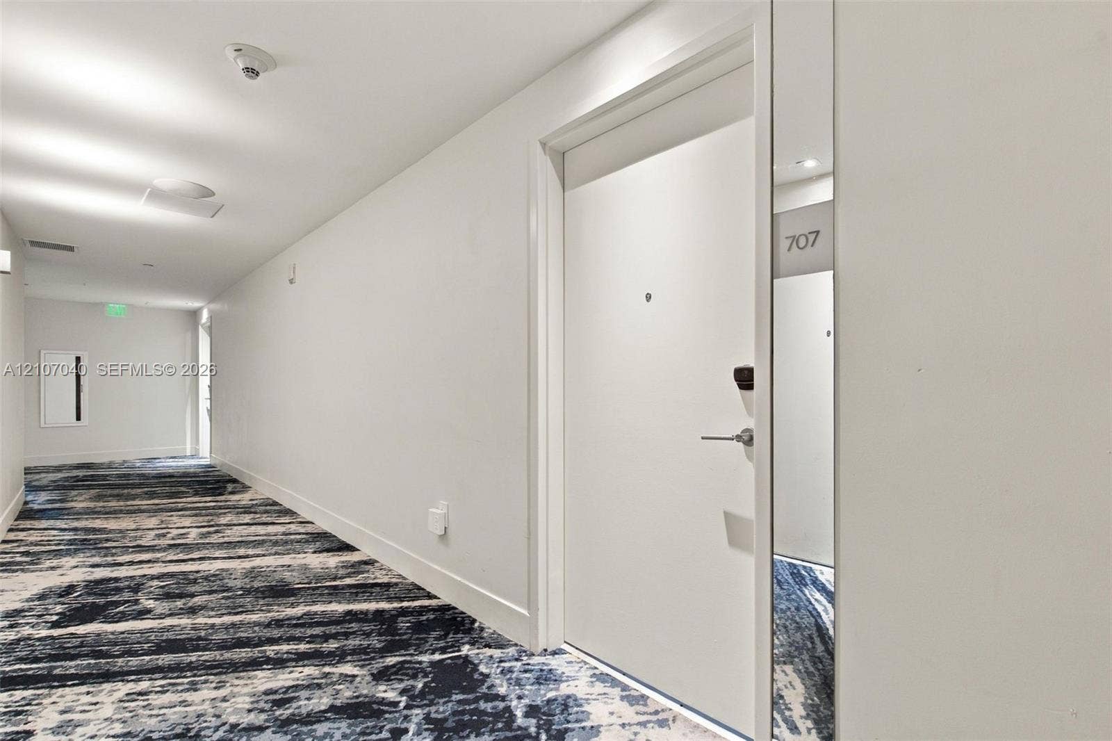 3101 Bayshore Drive, #707, Fort Lauderdale, FL 33304 Hallway featuring patterned wall-to-wall carpeting, recessed ceiling lighting, and a white entry door equipped with a digital keypad lock