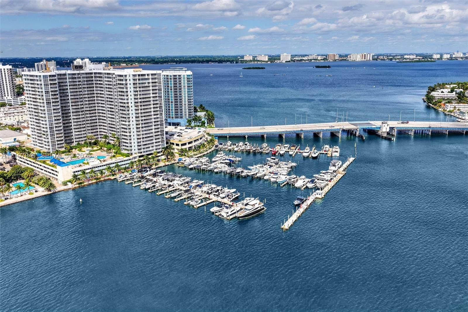 Waterfront high-rise complex featuring a private marina, boat slips, and an outdoor swimming pool