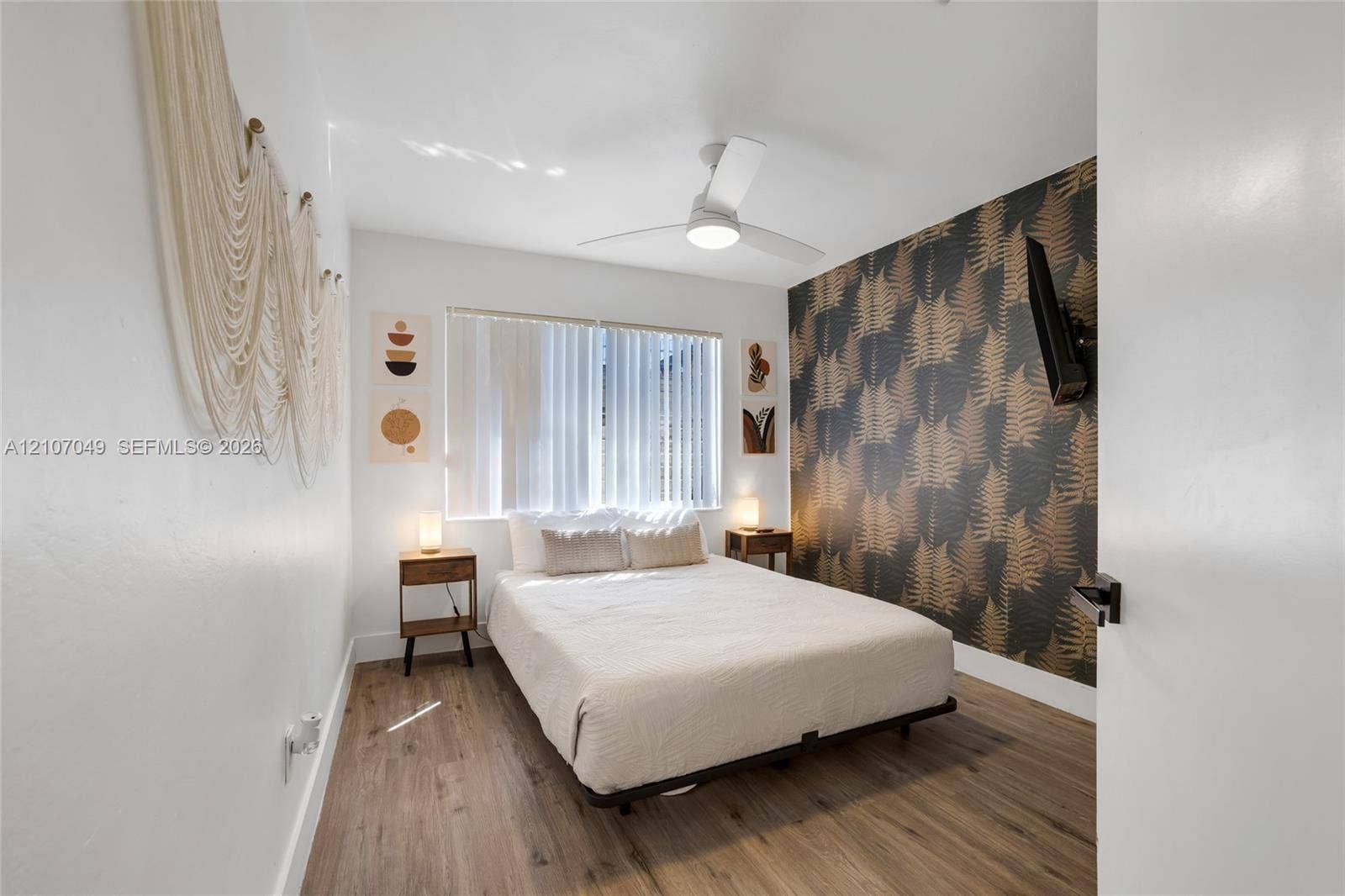 1009 NE 18th Street, Fort Lauderdale, FL 33305 Wood-finish flooring, patterned accent wall, and ceiling fan with integrated lighting