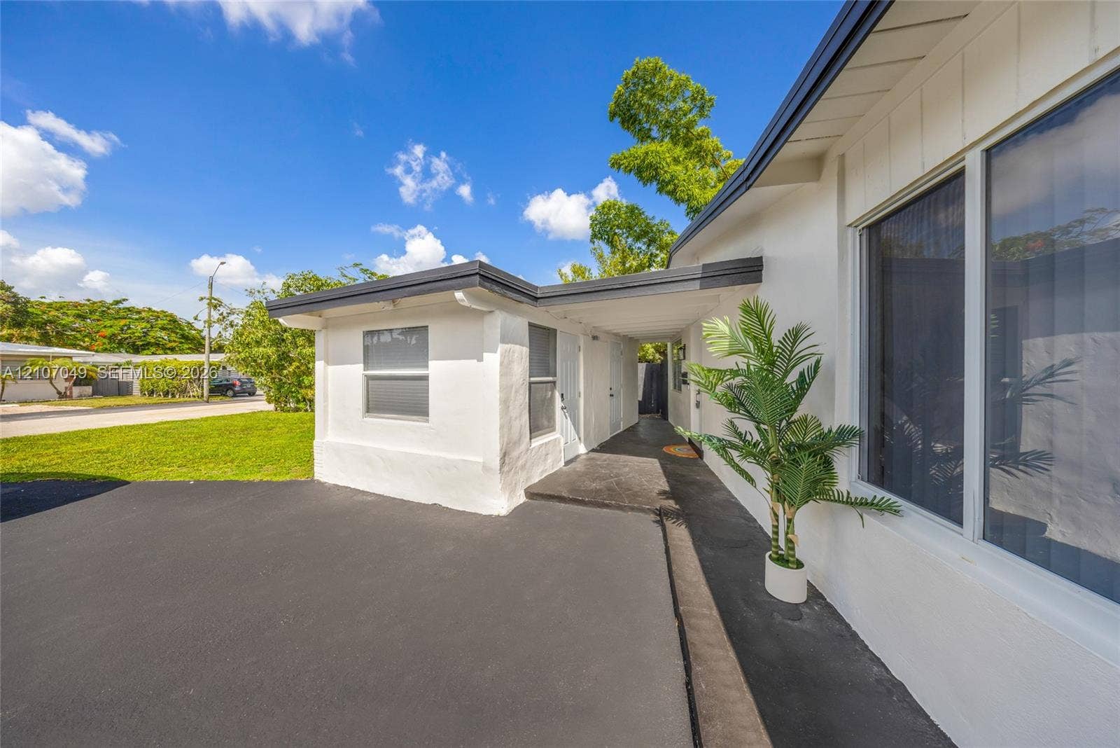 1009 NE 18th Street, Fort Lauderdale, FL 33305 Exterior featuring a smooth-finish white facade, asphalt driveway, covered entryway, and large-pane windows with dark framing