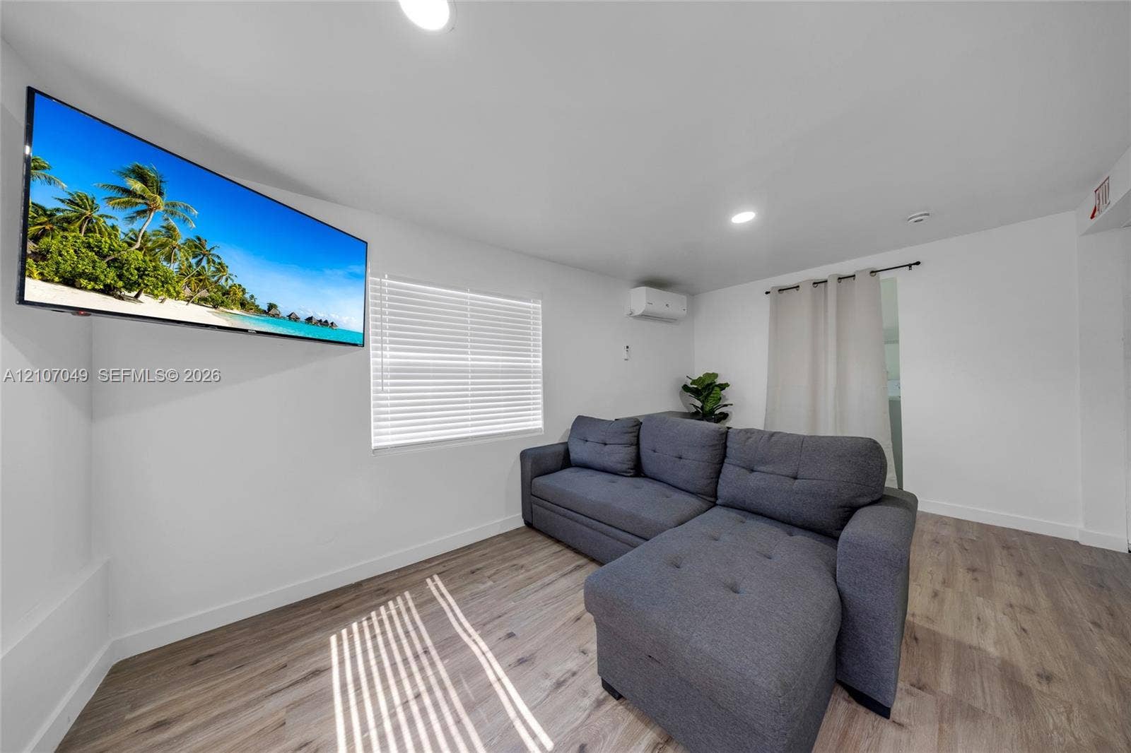 1009 NE 18th Street, Fort Lauderdale, FL 33305 Room featuring wood-finish flooring, recessed lighting, wall-mounted ductless heating and cooling unit, and horizontal window blinds