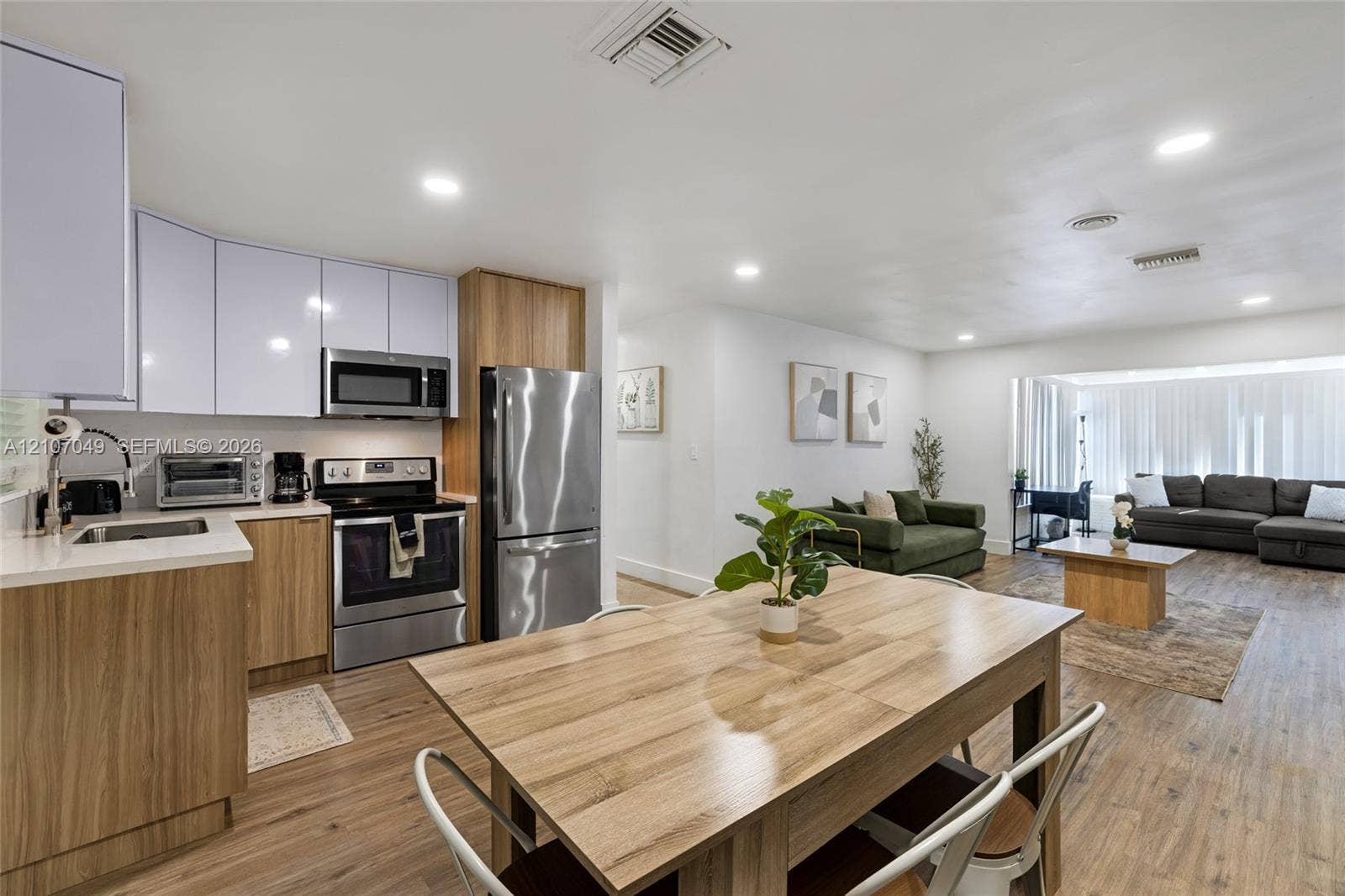 1009 NE 18th Street, Fort Lauderdale, FL 33305 Kitchen featuring wood-finish cabinetry, white upper cabinets, stainless steel appliances, and wood-finish flooring