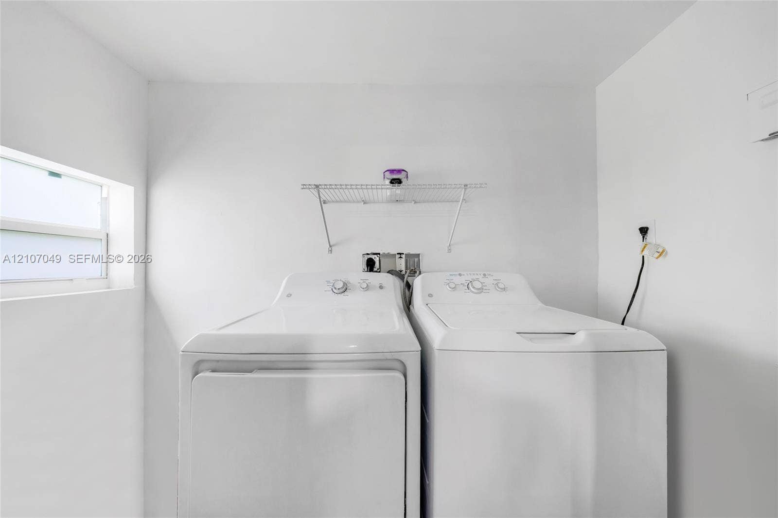1009 NE 18th Street, Fort Lauderdale, FL 33305 Laundry area featuring a window, built-in wire shelving, and dedicated utility hookups