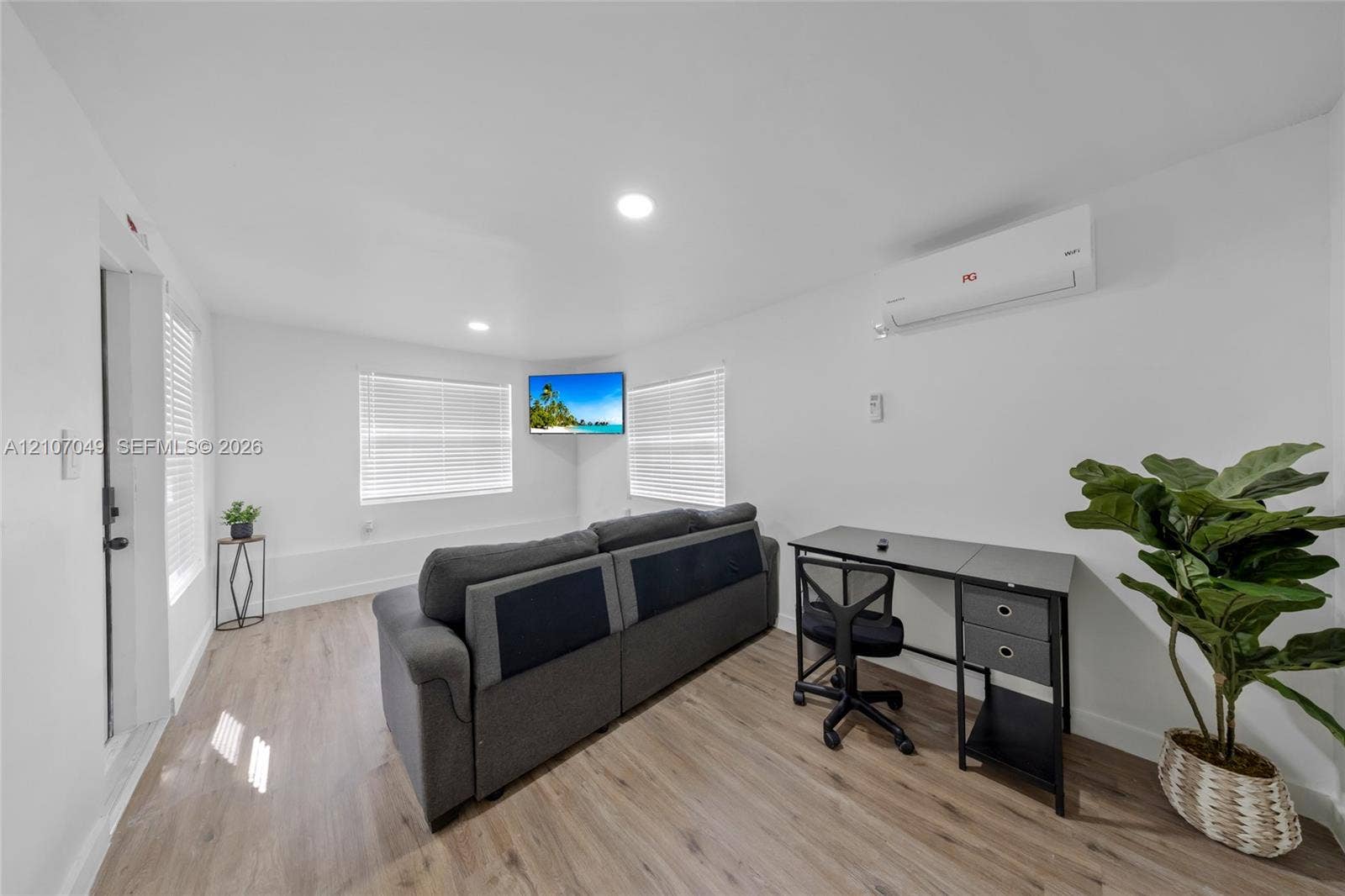 1009 NE 18th Street, Fort Lauderdale, FL 33305 Neutral-toned interior space featuring wood-finish flooring, recessed lighting, white walls, horizontal window blinds, and a wall-mounted ductless air conditioning unit
