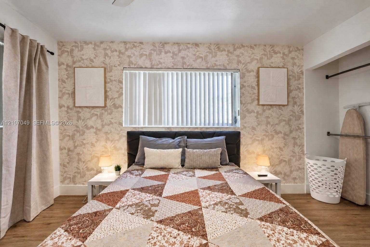 1009 NE 18th Street, Fort Lauderdale, FL 33305 Neutral-toned patterned wallpaper, wood-finish flooring, horizontal window blinds, and recessed closet space with built-in metal rods