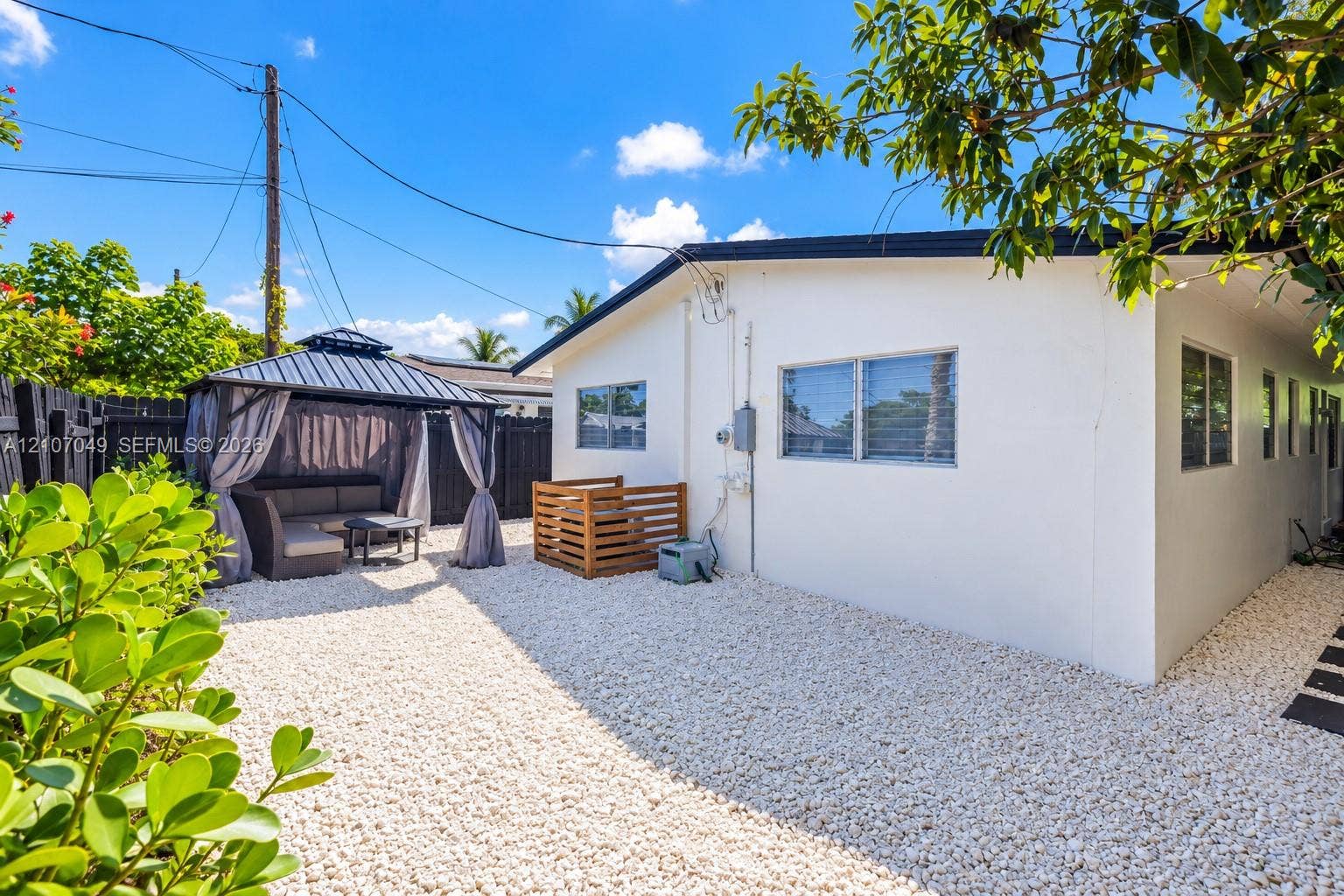 1009 NE 18th Street, Fort Lauderdale, FL 33305 Private backyard featuring a gravel ground cover, a detached metal-frame gazebo, and perimeter wood privacy fencing
