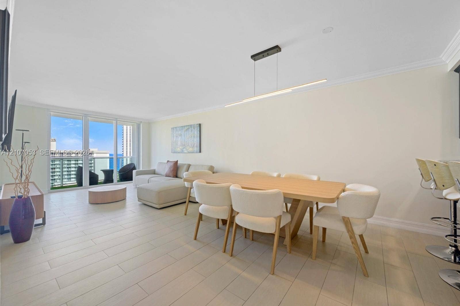 19370 Collins Avenue, #1403, Sunny Isles Beach, FL 33160 Open-concept living space featuring wood-finish flooring, linear pendant lighting, crown molding, and floor-to-ceiling sliding glass doors