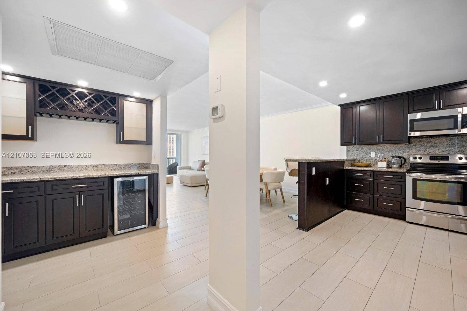 19370 Collins Avenue, #1403, Sunny Isles Beach, FL 33160 Kitchen featuring dark wood cabinetry, stone countertops, stainless steel appliances, built-in wine cooler, and tile flooring