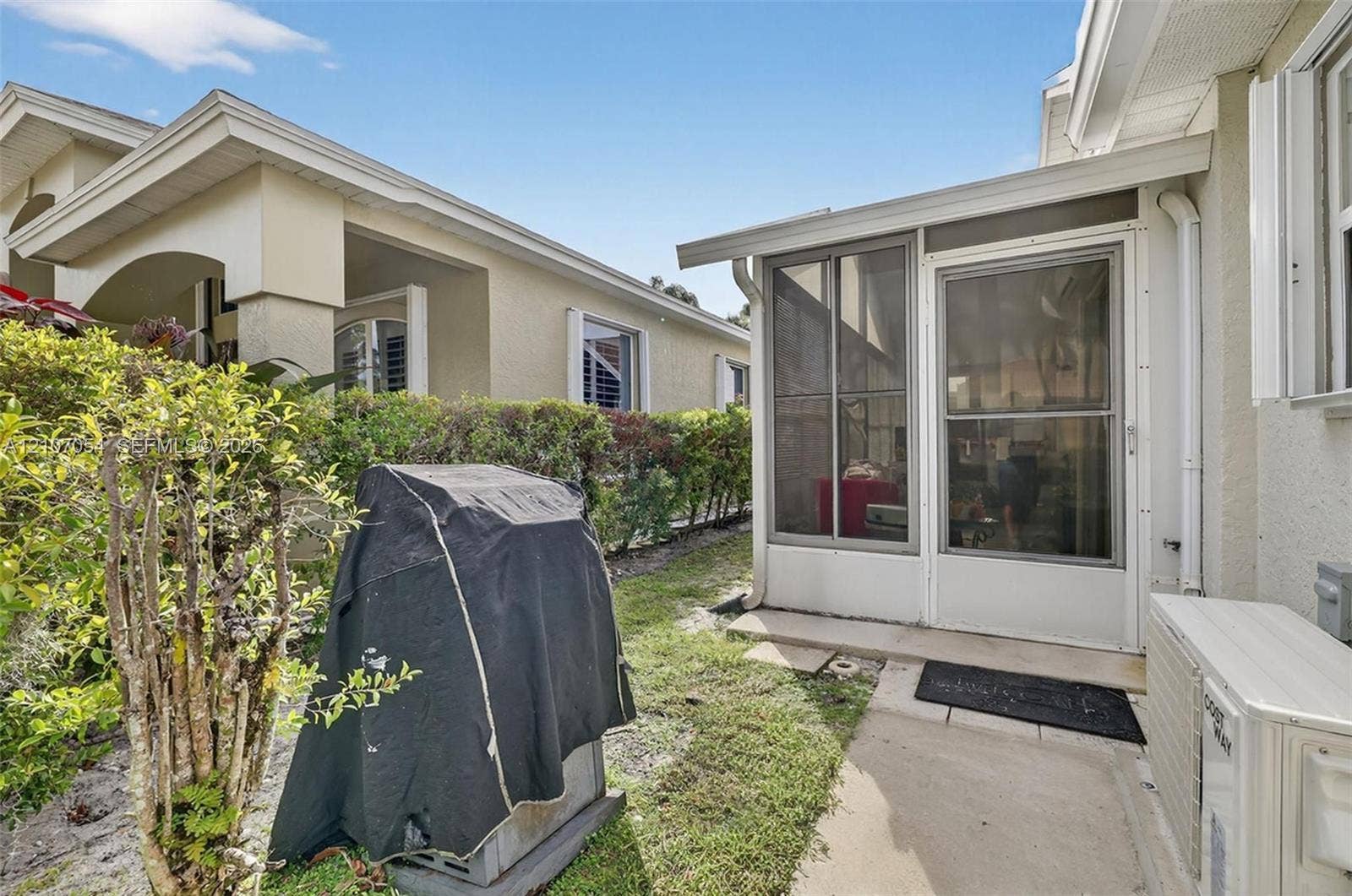 Stucco exterior featuring concrete walkway and landscaped shrubs
