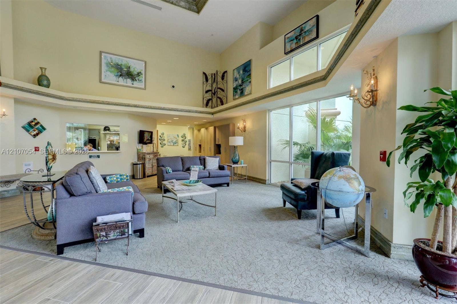 210 NW Zanzibar Place, Port St Lucie, FL 34986 Clubhouse: Open-concept room featuring vaulted ceilings, floor-to-ceiling windows, built-in shelving, decorative wall-mounted lighting, and neutral-tone carpeting