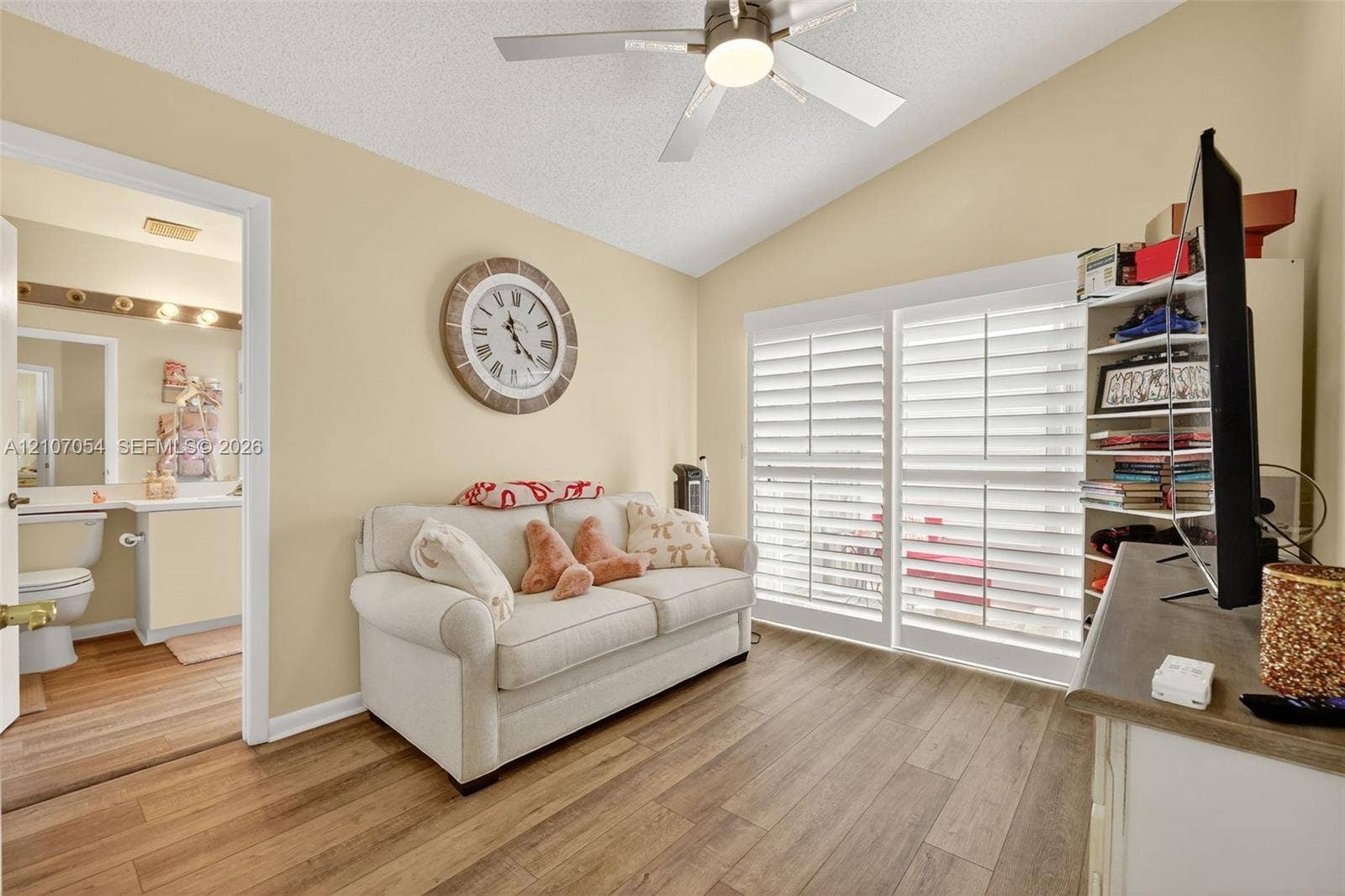 210 NW Zanzibar Place, Port St Lucie, FL 34986 Vaulted ceiling with a centrally mounted ceiling fan, laminate flooring, and white plantation shutters